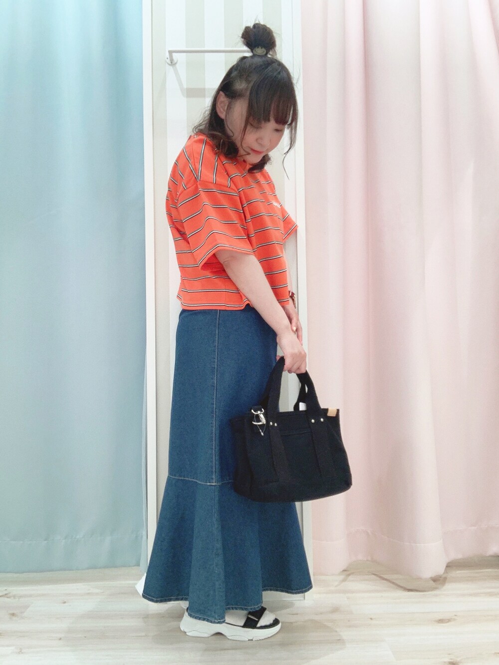 オレンジ系のTシャツ/カットソー、ブルー系のスカート、ブラック系のトートバッグを着用したレディースの夏コーディネートの2枚目の写真