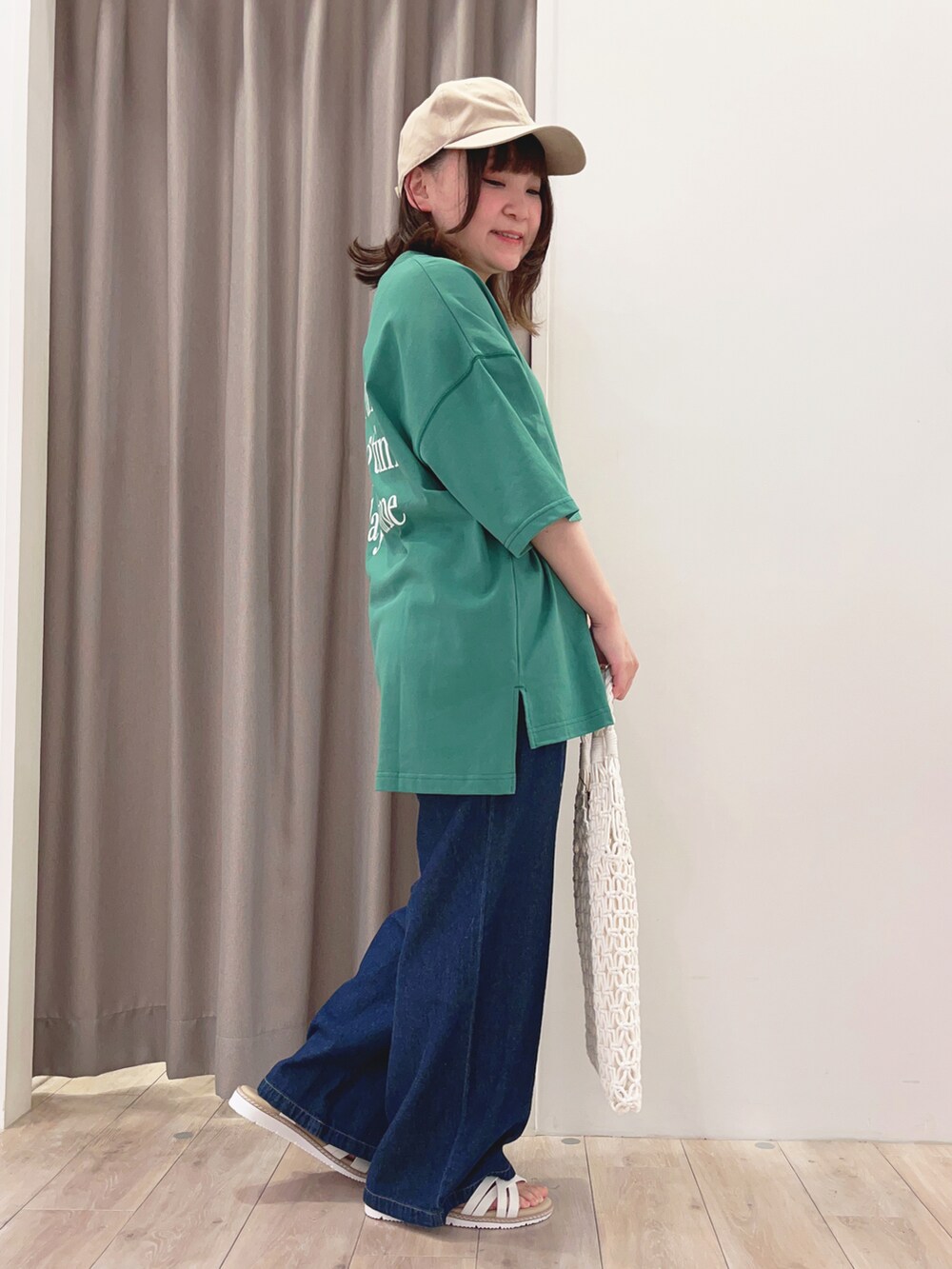 グリーン系のTシャツ/カットソー、ホワイト系のトートバッグ、ホワイト系のサンダルを着用したレディースの夏コーディネートの2枚目の写真