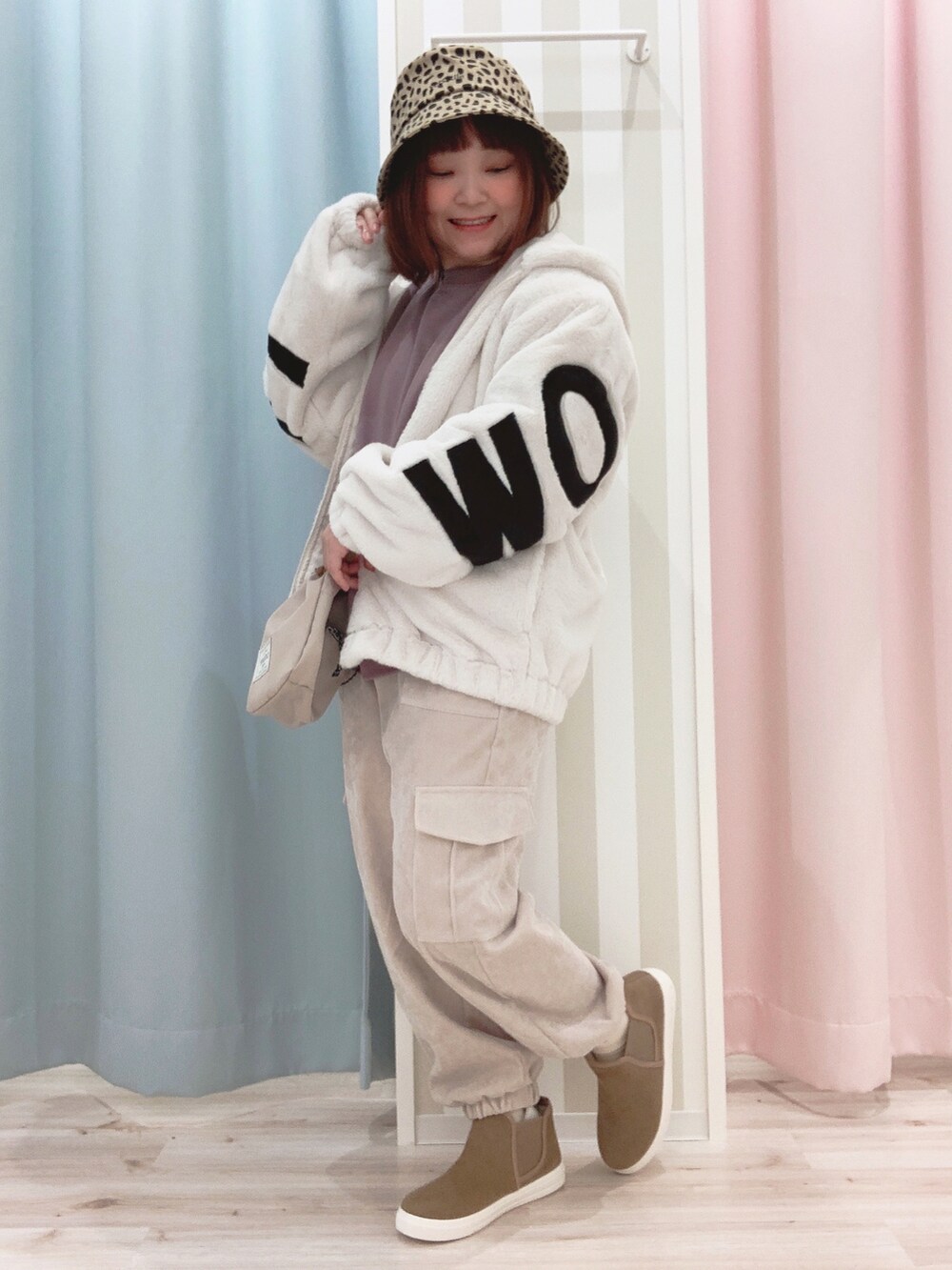 ホワイト系のブルゾン、パープル系のスウェット、ベージュ系のショルダーバッグを着用したレディースの冬コーディネートの2枚目の写真