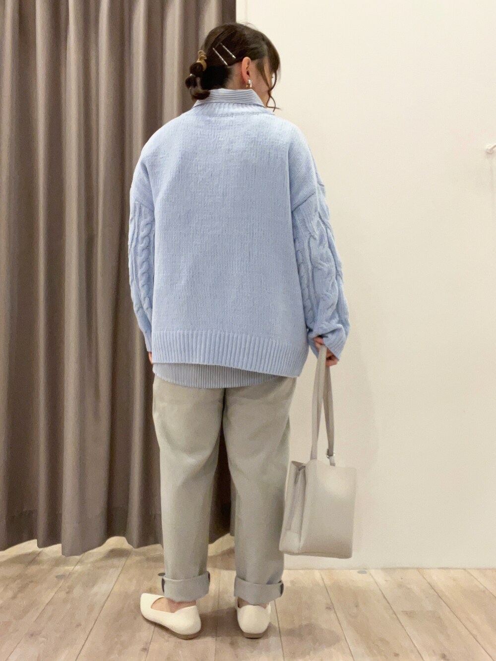 グレー系のショルダーバッグ、ベージュ系のパンプス、ブルー系のニット/セーターを着用したレディースの春コーディネートの3枚目の写真