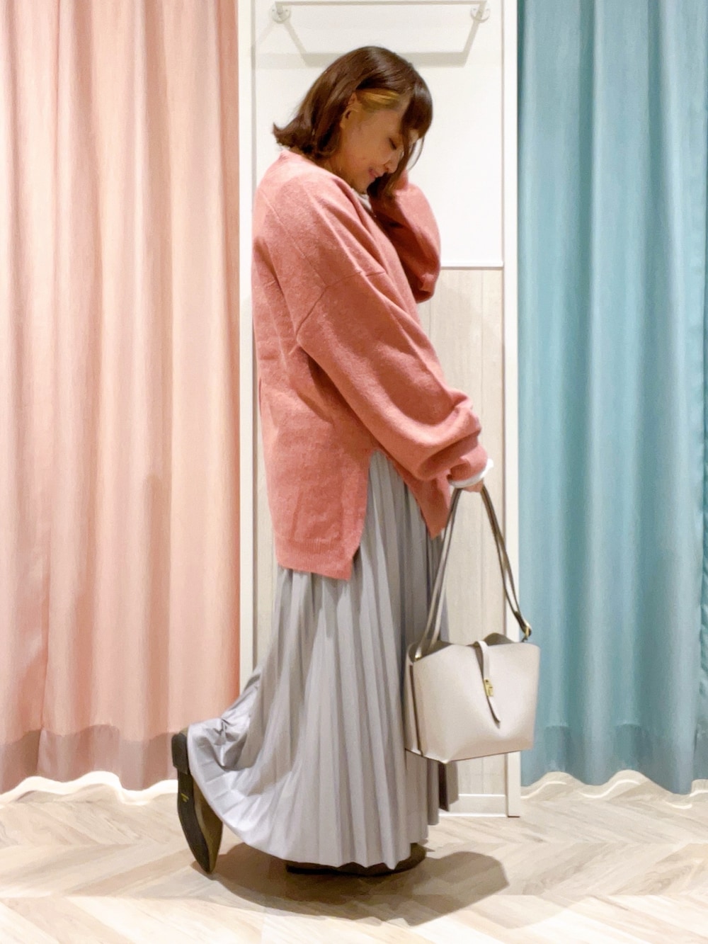 ピンク系のニット/セーター、ホワイト系のTシャツ/カットソー、グレー系のスカートを着用したレディースの冬コーディネートの2枚目の写真