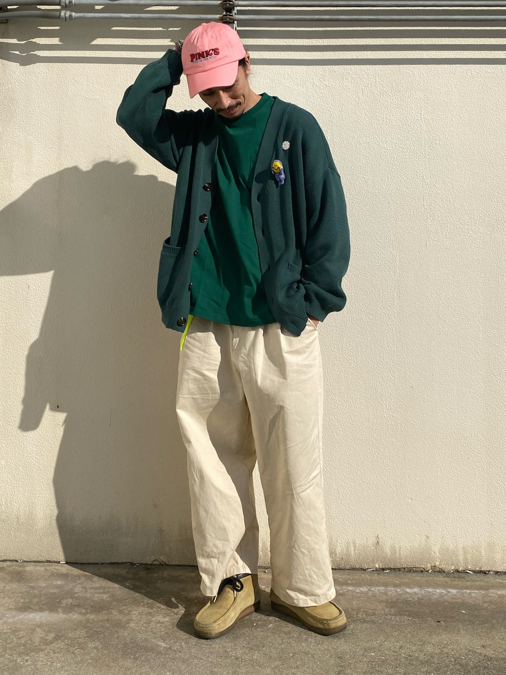 ホワイト系のチノパンツ、ベージュ系のブーツ、グリーン系のカーディガン/ボレロを着用したメンズの春コーディネートの2枚目の写真