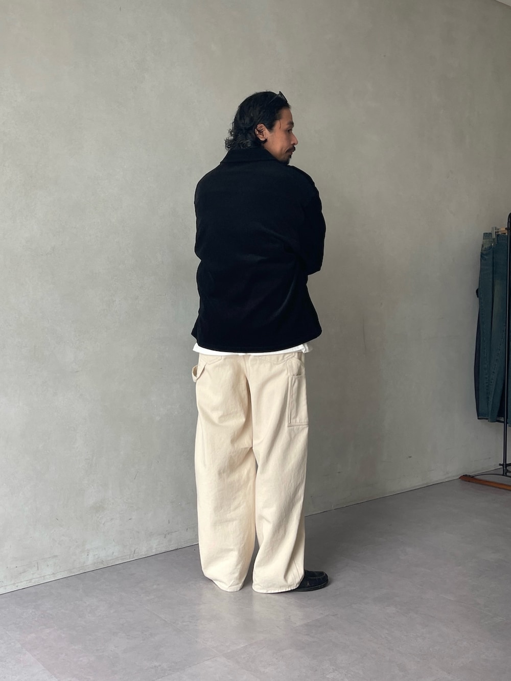 ブラック系のテーラードジャケット、ブルー系のニット/セーター、ホワイト系のデニムパンツを着用したメンズの秋コーディネートの2枚目の写真