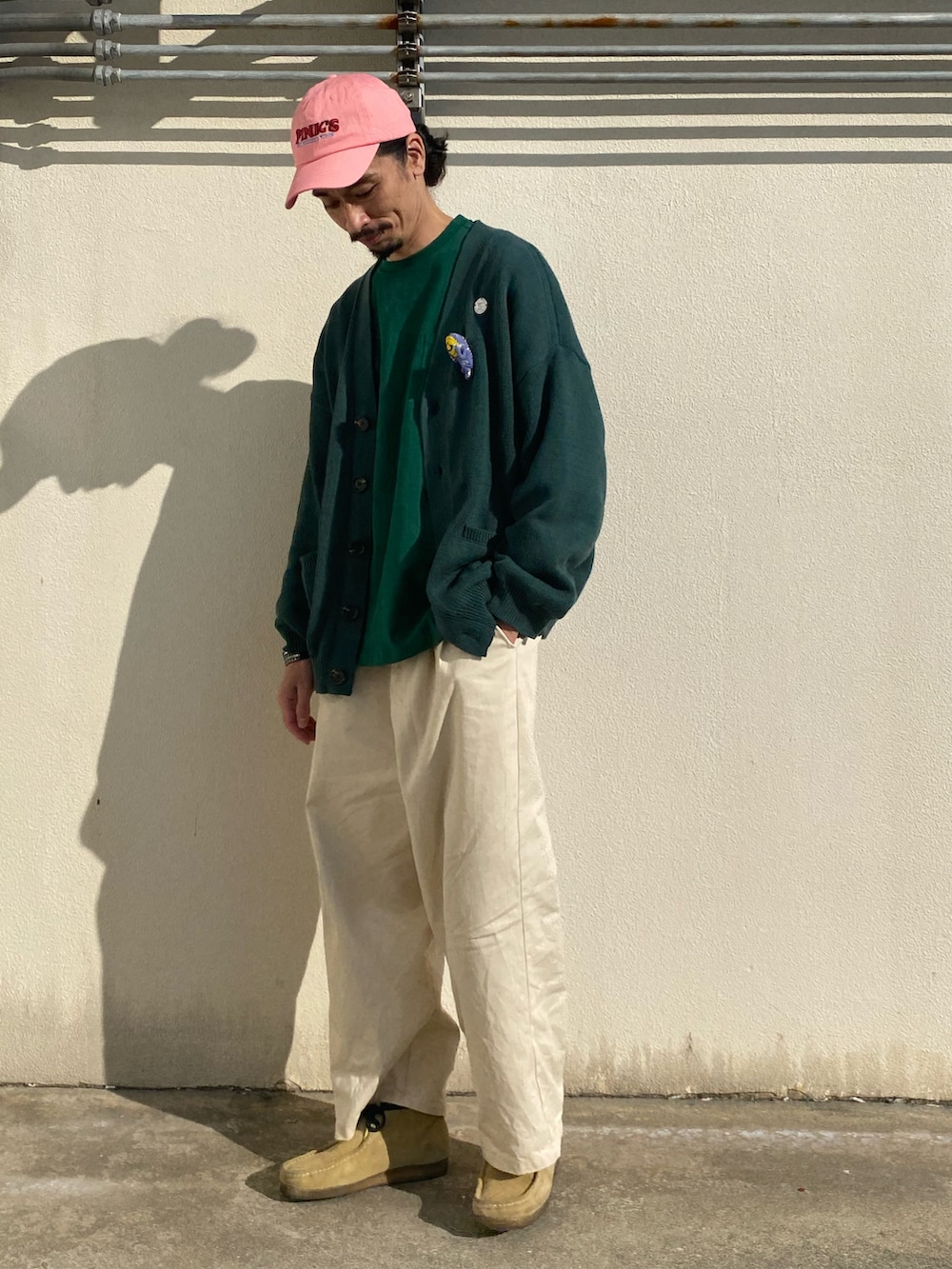 ホワイト系のチノパンツ、ベージュ系のブーツ、グリーン系のカーディガン/ボレロを着用したメンズの春コーディネートの3枚目の写真