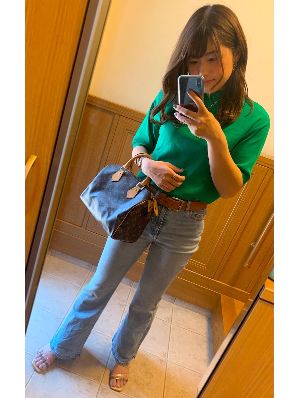 グリーン系のニット/セーター、ブルー系のデニムパンツ、ブラウン系のボストンバッグを着用したレディースの夏コーディネートの2枚目の写真