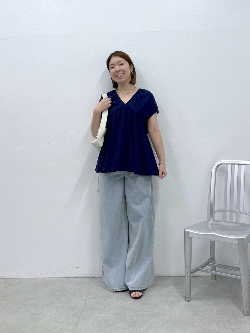 ブルー系のTシャツ/カットソー、ブルー系のデニムパンツ、ホワイト系のショルダーバッグを着用したレディースの夏コーディネートの4枚目の写真