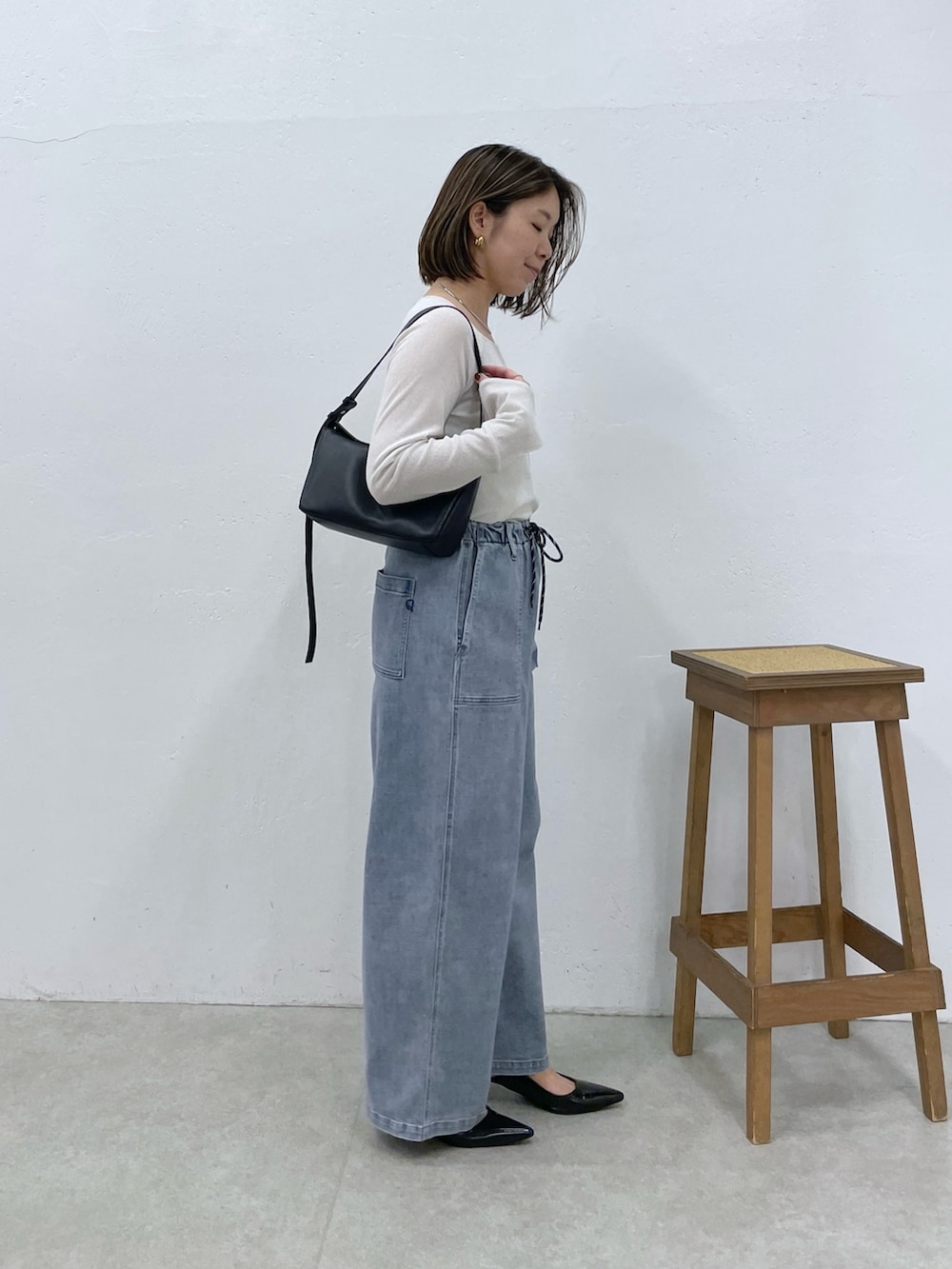 ブルー系のデニムパンツ、ブラック系のショルダーバッグ、ホワイト系のTシャツ/カットソーを着用したレディースの夏コーディネートの3枚目の写真