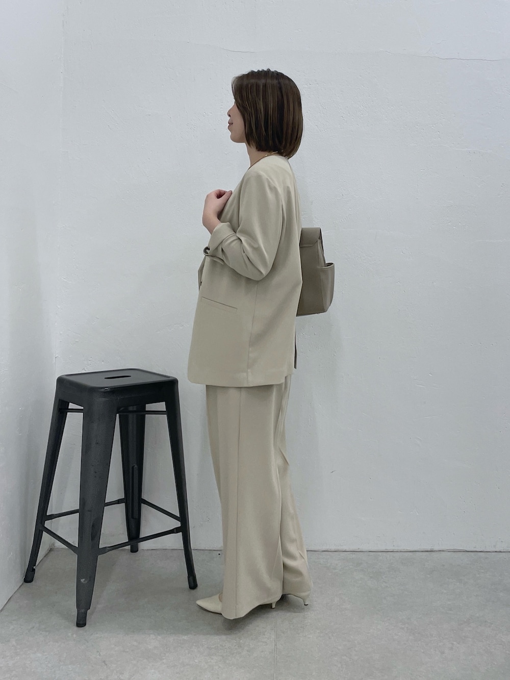 ベージュ系のスラックス、ベージュ系のノーカラージャケット、ホワイト系のキャミソールを着用したレディースの冬コーディネートの2枚目の写真