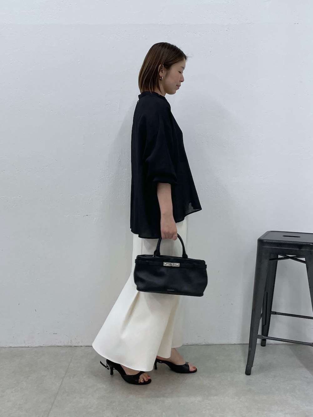 ホワイト系のスカート、ブラック系のトートバッグ、ブラック系のシャツ/ブラウスを着用したレディースの春コーディネートの2枚目の写真