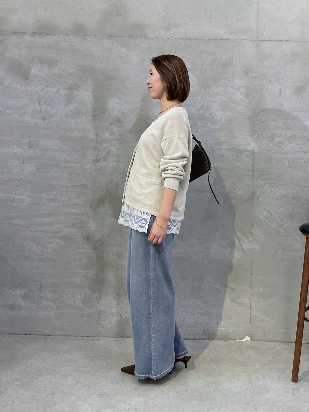 ベージュ系のカーディガン/ボレロ、ホワイト系のキャミソール、ブルー系のデニムパンツを着用したレディースの冬コーディネートの2枚目の写真