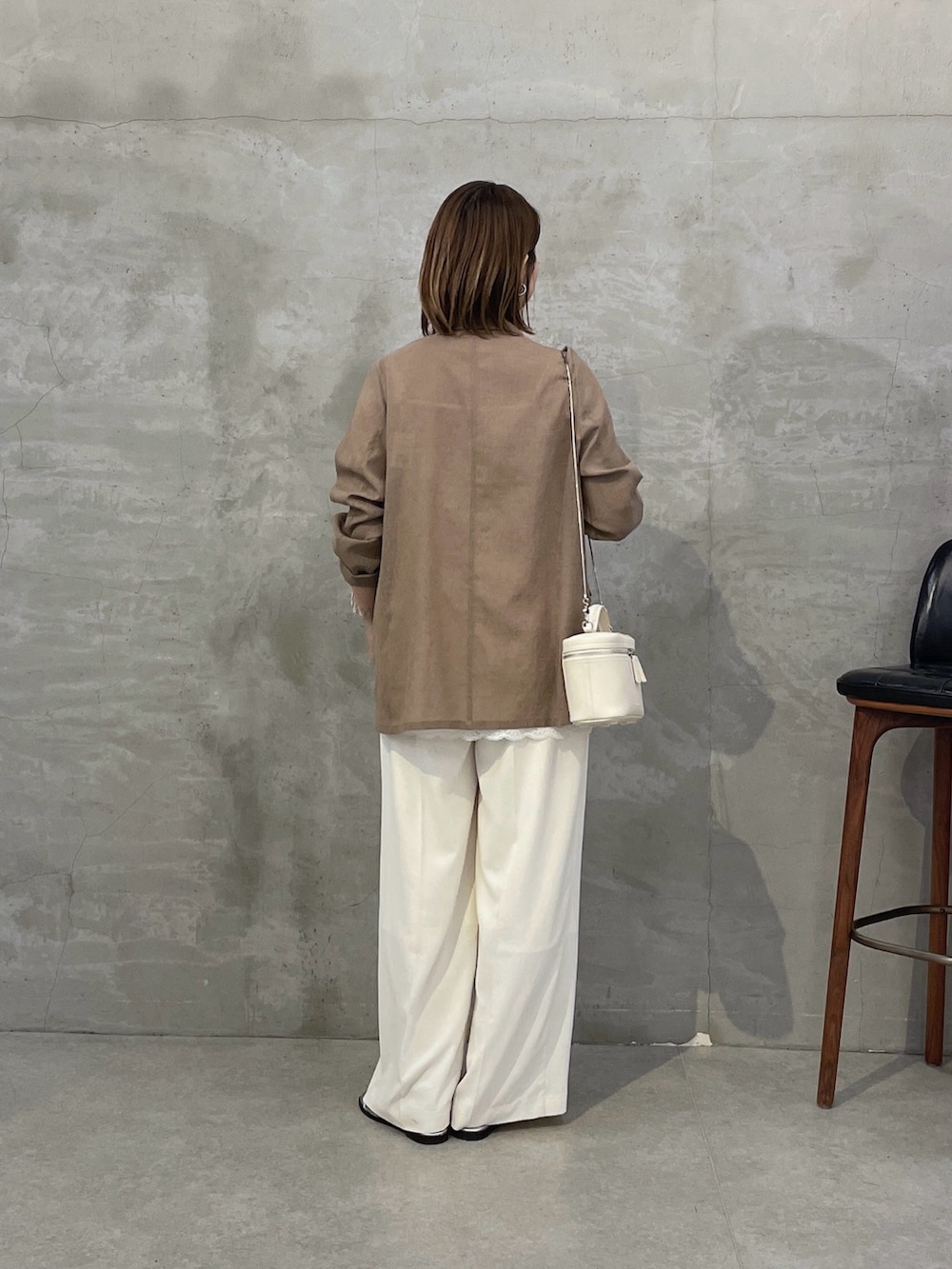 ベージュ系のテーラードジャケット、ホワイト系のキャミソール、ホワイト系のスラックスを着用したレディースの春コーディネートの2枚目の写真