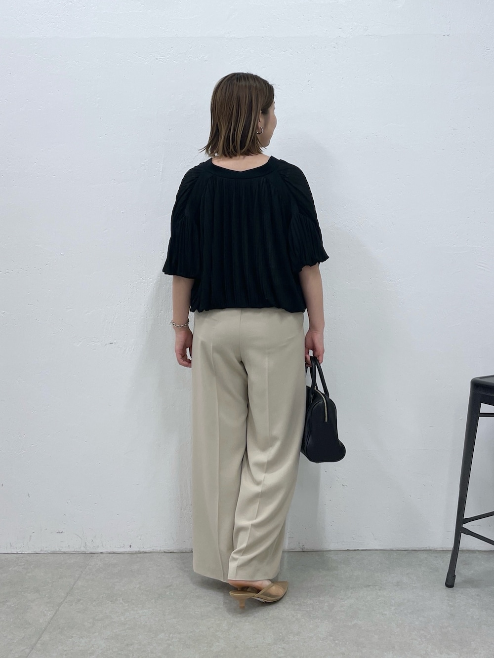 ブラック系のTシャツ/カットソー、ベージュ系のスラックス、ブラック系のボストンバッグを着用したレディースの夏コーディネートの2枚目の写真