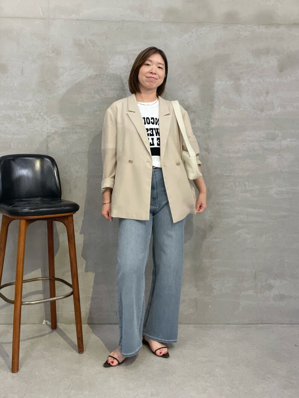 ブルー系のデニムパンツ、ベージュ系のテーラードジャケット、ホワイト系のショルダーバッグを着用したレディースの夏コーディネートの5枚目の写真