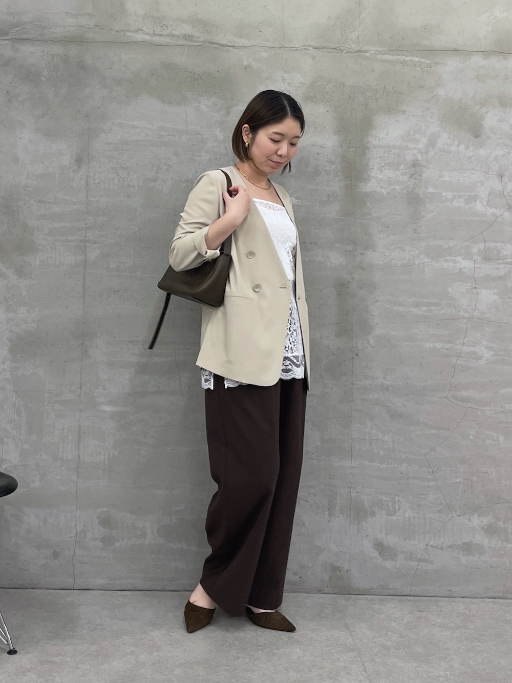 ベージュ系のノーカラージャケット、ホワイト系のキャミソール、ブラウン系のスラックスを着用したレディースの冬コーディネートの4枚目の写真
