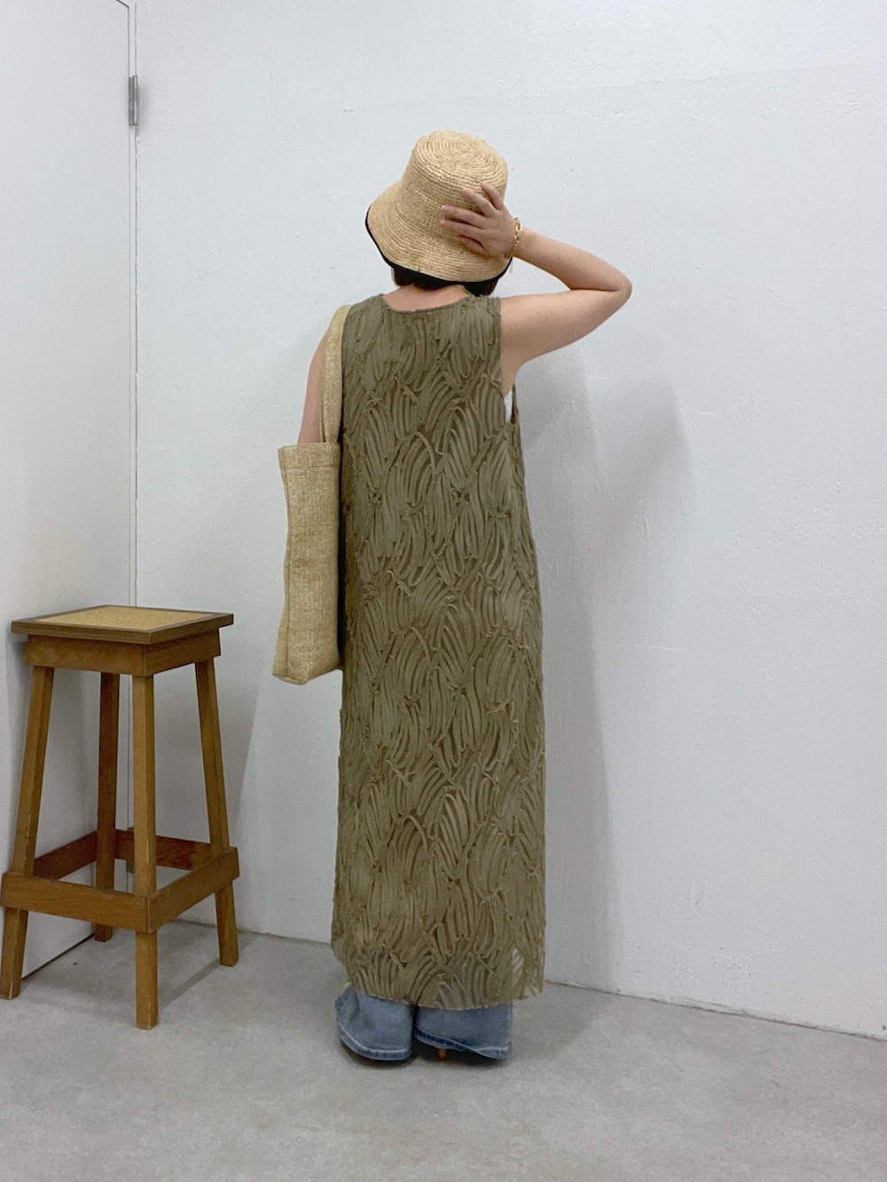 ブルー系のデニムパンツ、グリーン系のワンピース、ベージュ系のトートバッグを着用したレディースの夏コーディネートの2枚目の写真