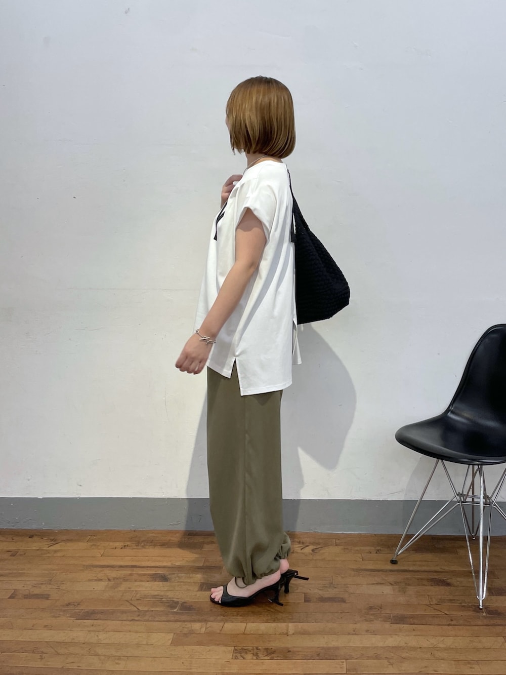 ブラック系のトートバッグ、ホワイト系のTシャツ/カットソー、グリーン系のスラックスを着用したレディースの夏コーディネートの2枚目の写真