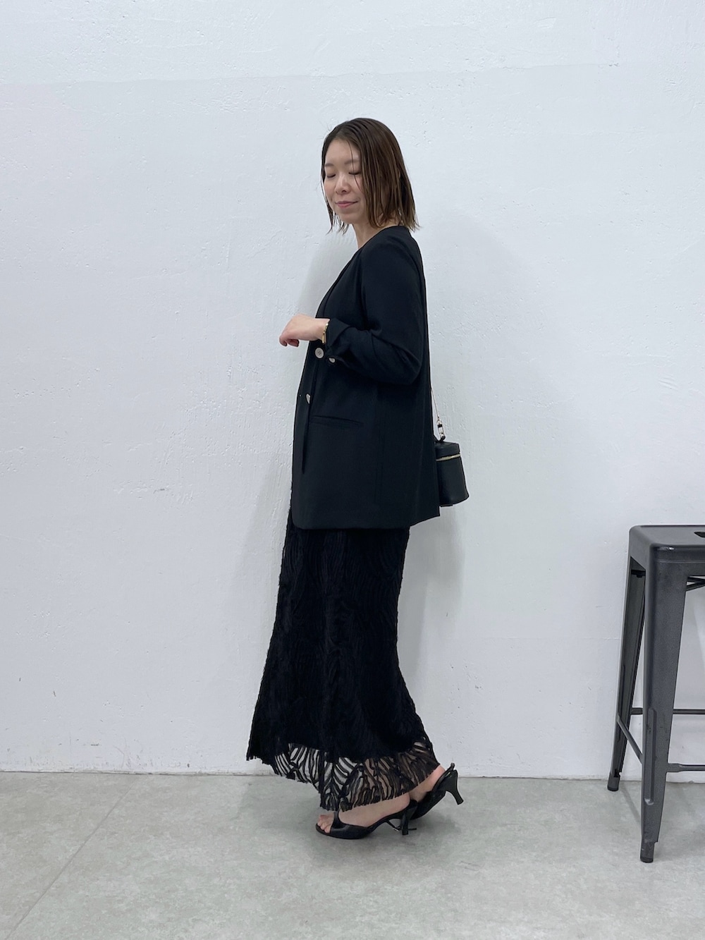 ブラック系のノーカラージャケット、ブラック系のワンピースを着用したレディースの春コーディネートの2枚目の写真