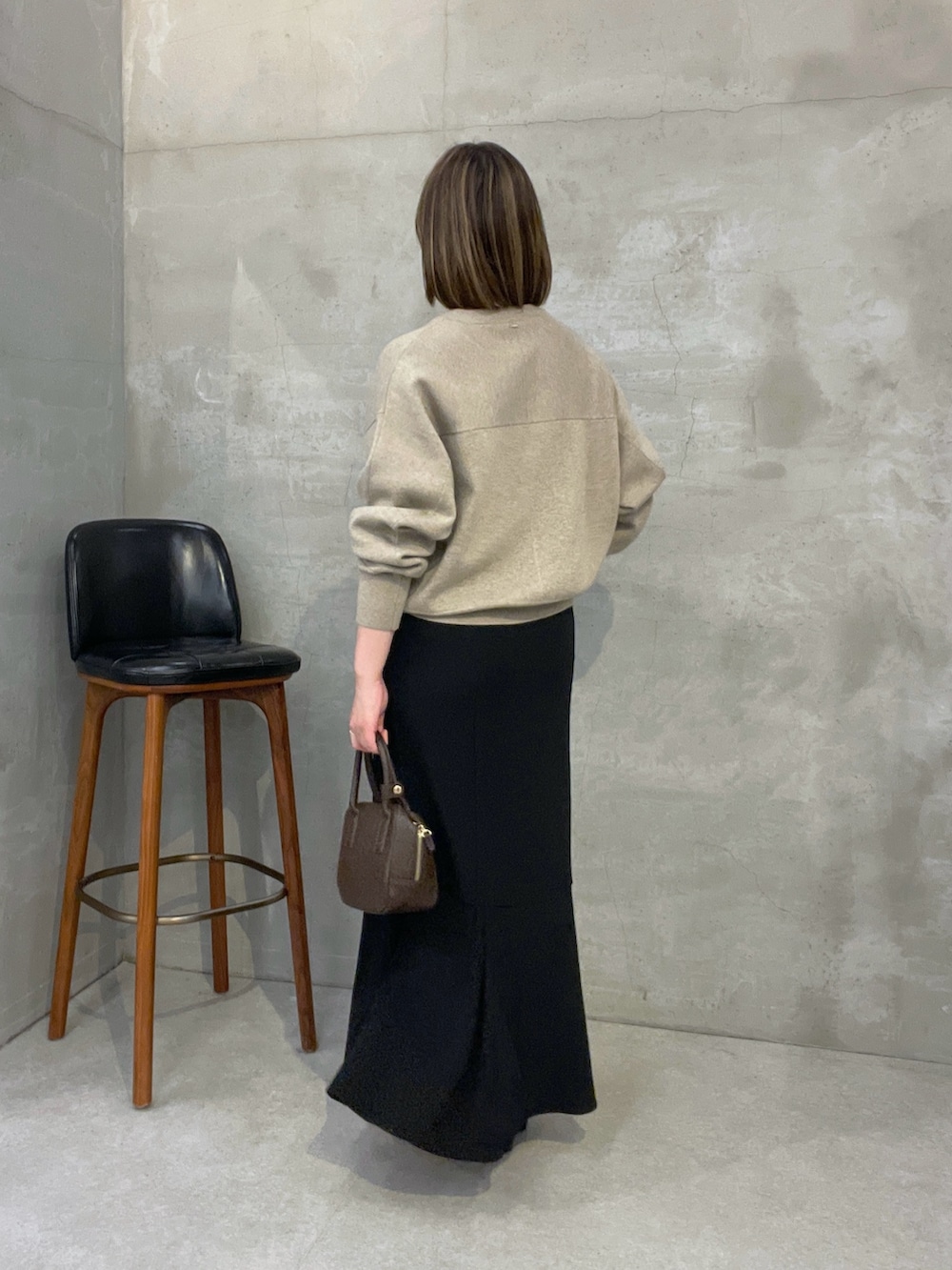 ベージュ系のニット/セーター、ブラック系のスカート、ブラウン系のショルダーバッグを着用したレディースの夏コーディネートの3枚目の写真