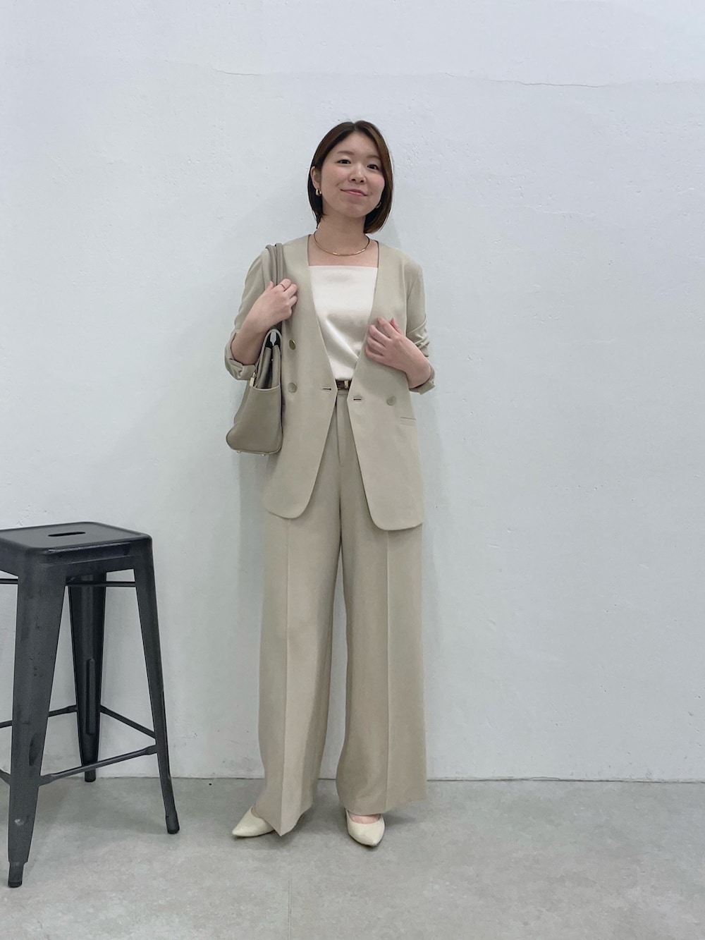 ベージュ系のスラックス、ベージュ系のノーカラージャケット、ホワイト系のキャミソールを着用したレディースの冬コーディネートの5枚目の写真