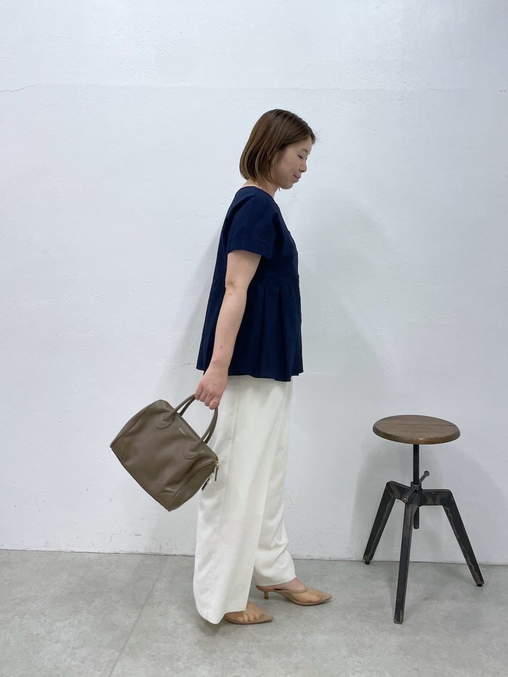 ブルー系のシャツ/ブラウス、ホワイト系のスラックス、ブラウン系のボストンバッグを着用したレディースの春コーディネートの2枚目の写真