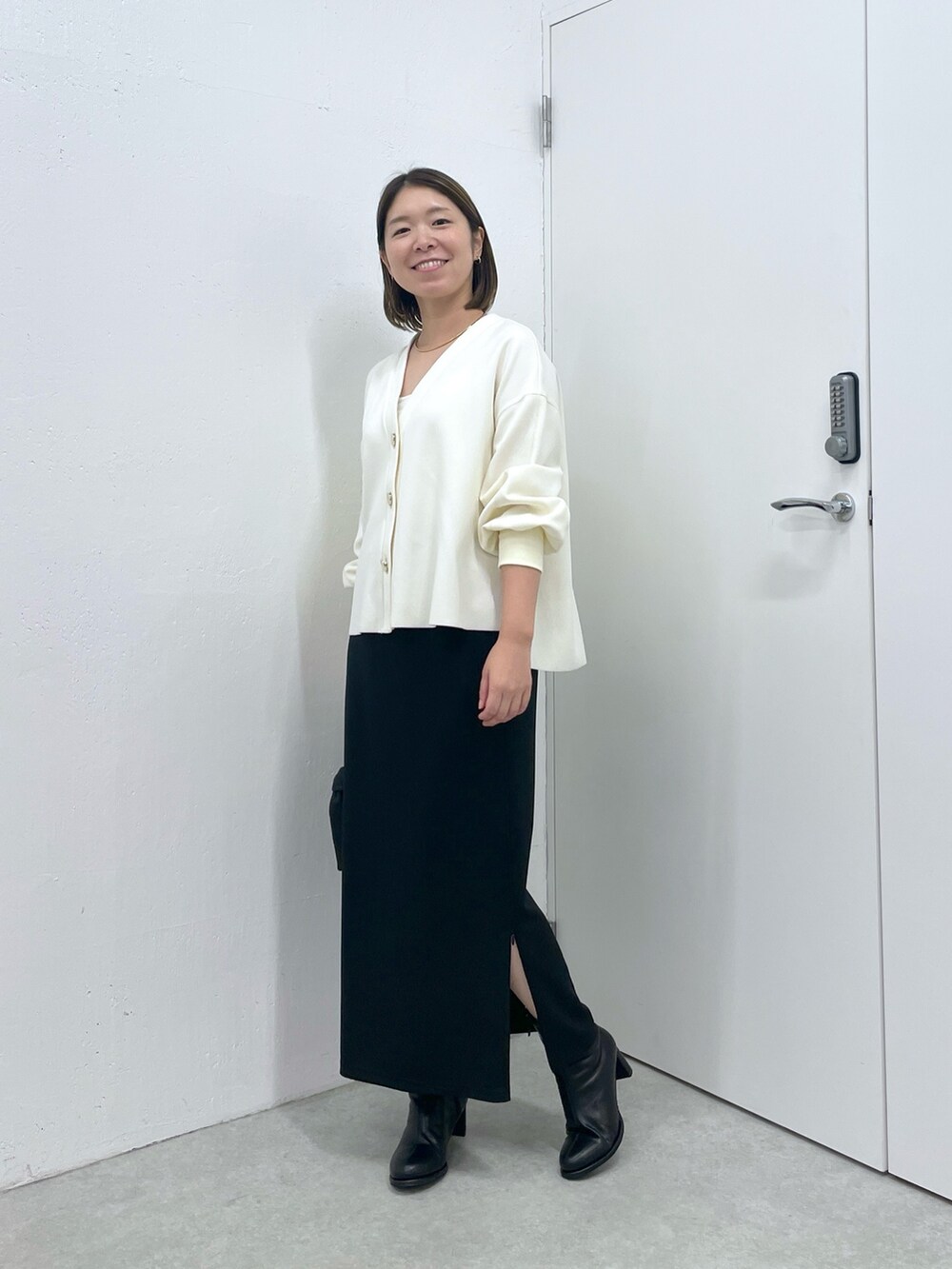 ホワイト系のカーディガン/ボレロ、ブラック系のスカート、ブラック系のショルダーバッグを着用したレディースの秋コーディネートの5枚目の写真