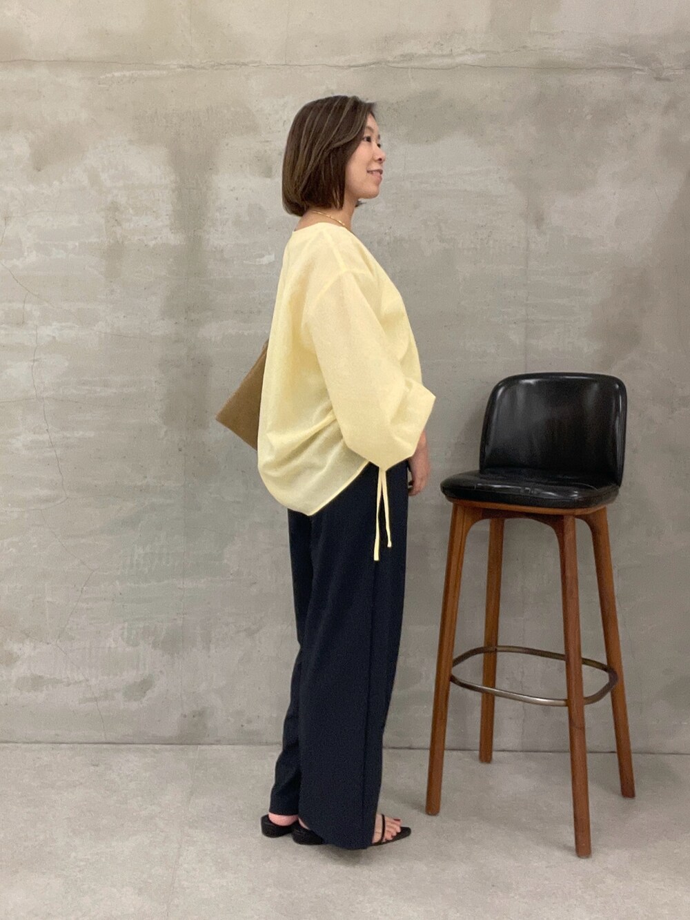 ブラック系のその他パンツ、ベージュ系のショルダーバッグ、イエロー系のシャツ/ブラウスを着用したレディースの夏コーディネートの3枚目の写真