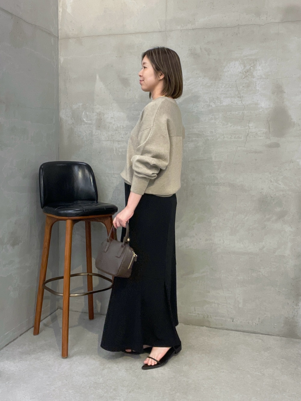 ベージュ系のニット/セーター、ブラック系のスカート、ブラウン系のショルダーバッグを着用したレディースの夏コーディネートの4枚目の写真
