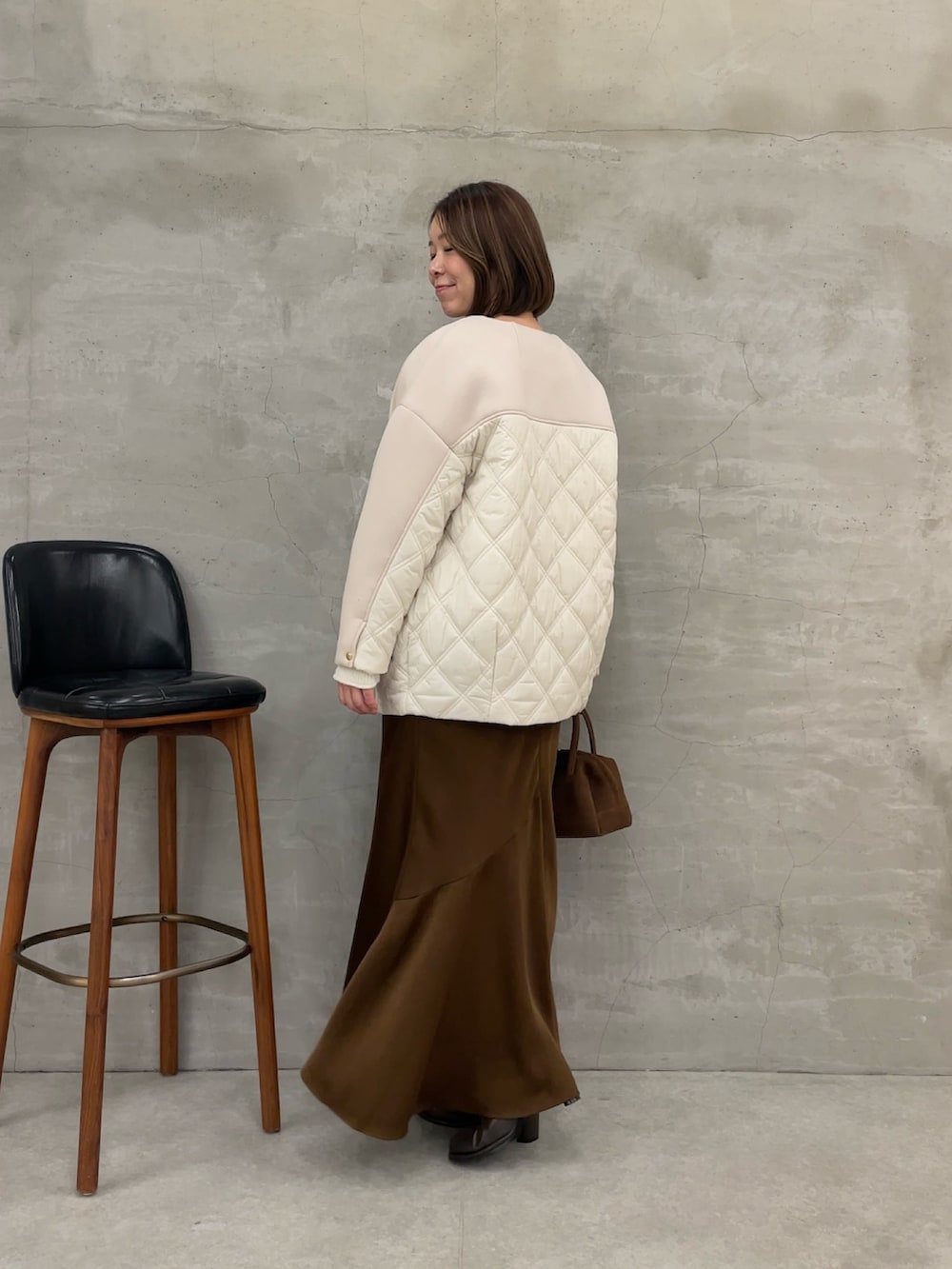 ブラウン系のスカート、ホワイト系のTシャツ/カットソー、ホワイト系のニット/セーターを着用したレディースの秋コーディネートの3枚目の写真