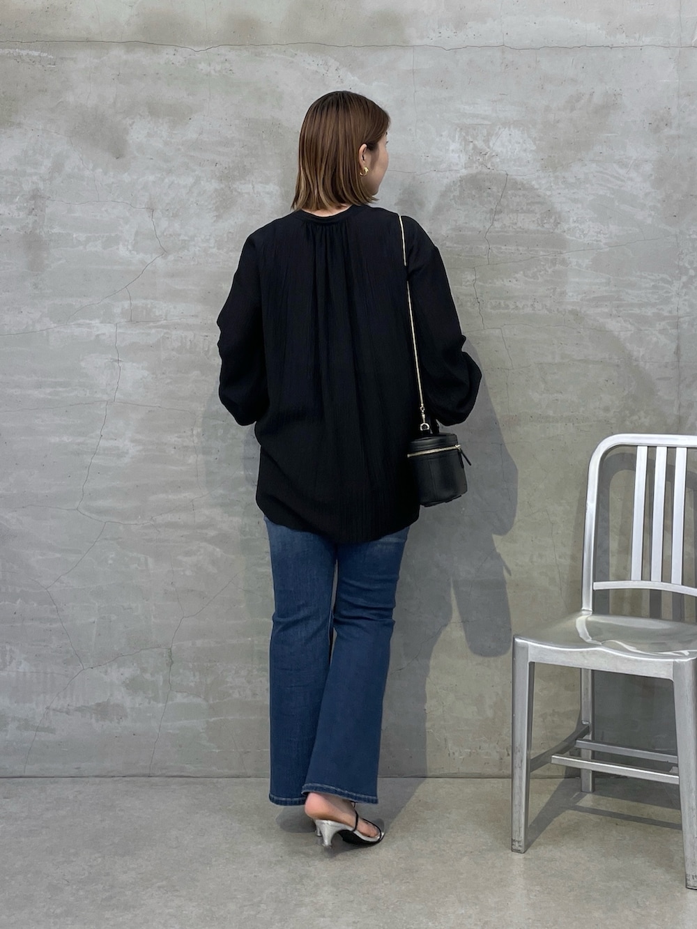 ブルー系のデニムパンツ、ブラック系のシャツ/ブラウス、ブラック系のショルダーバッグを着用したレディースの夏コーディネートの3枚目の写真