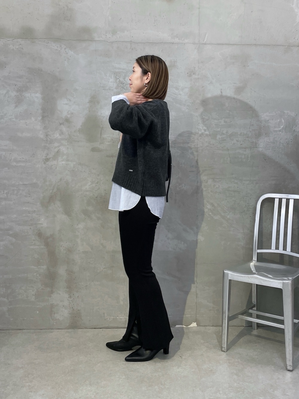 グレー系のニット/セーター、ホワイト系のTシャツ/カットソー、ブラック系のスラックスを着用したレディースの秋コーディネートの4枚目の写真