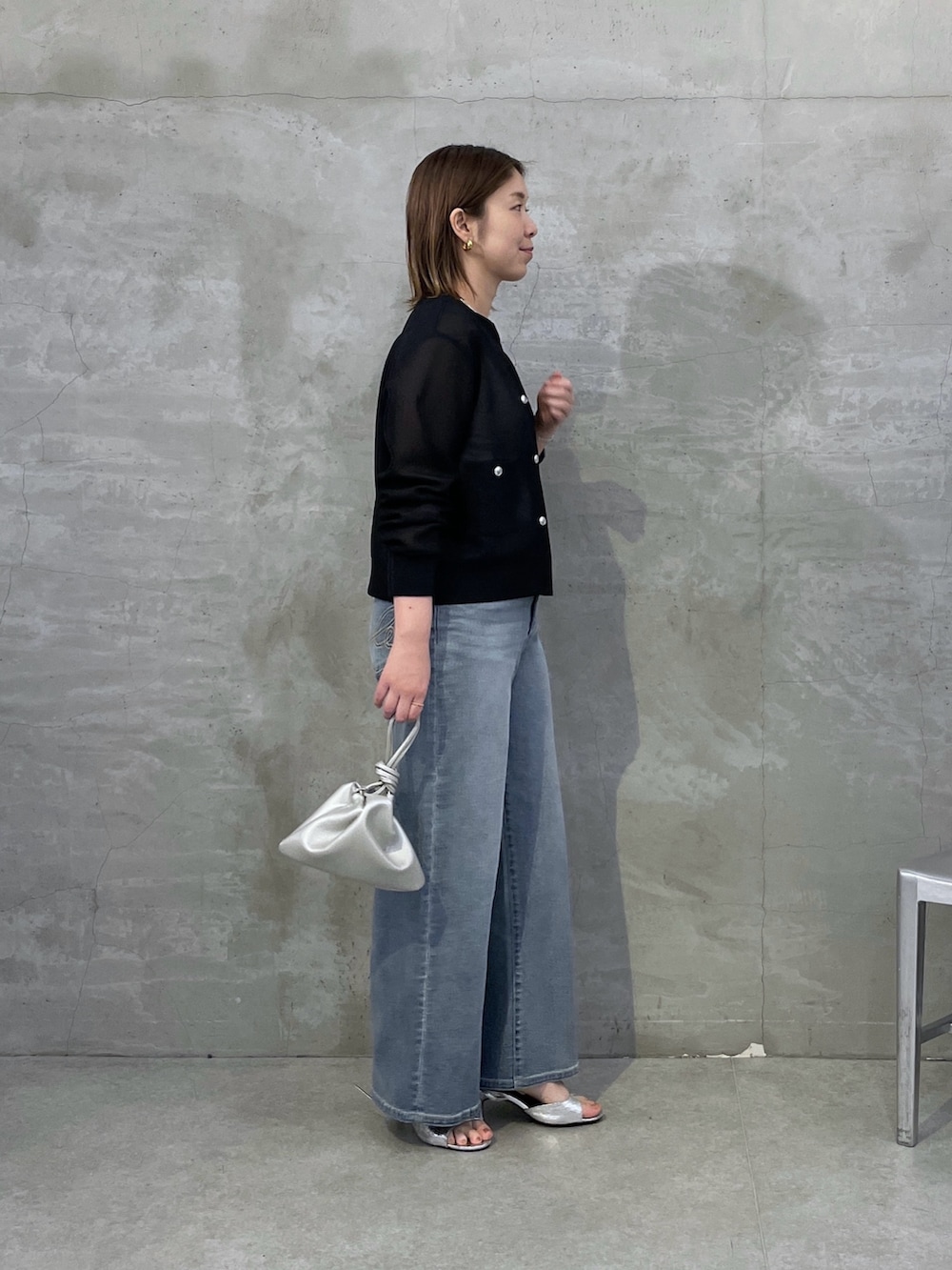 ブルー系のデニムパンツ、ブラック系のカーディガン/ボレロ、シルバー系のネックレスを着用したレディースの春コーディネートの4枚目の写真