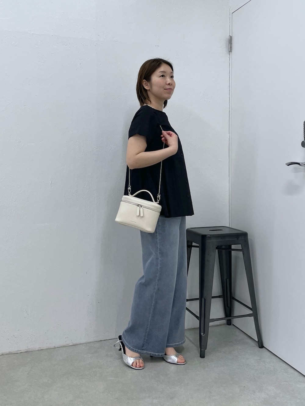 ブラック系のシャツ/ブラウス、ブルー系のデニムパンツ、ホワイト系のショルダーバッグを着用したレディースの春コーディネートの2枚目の写真