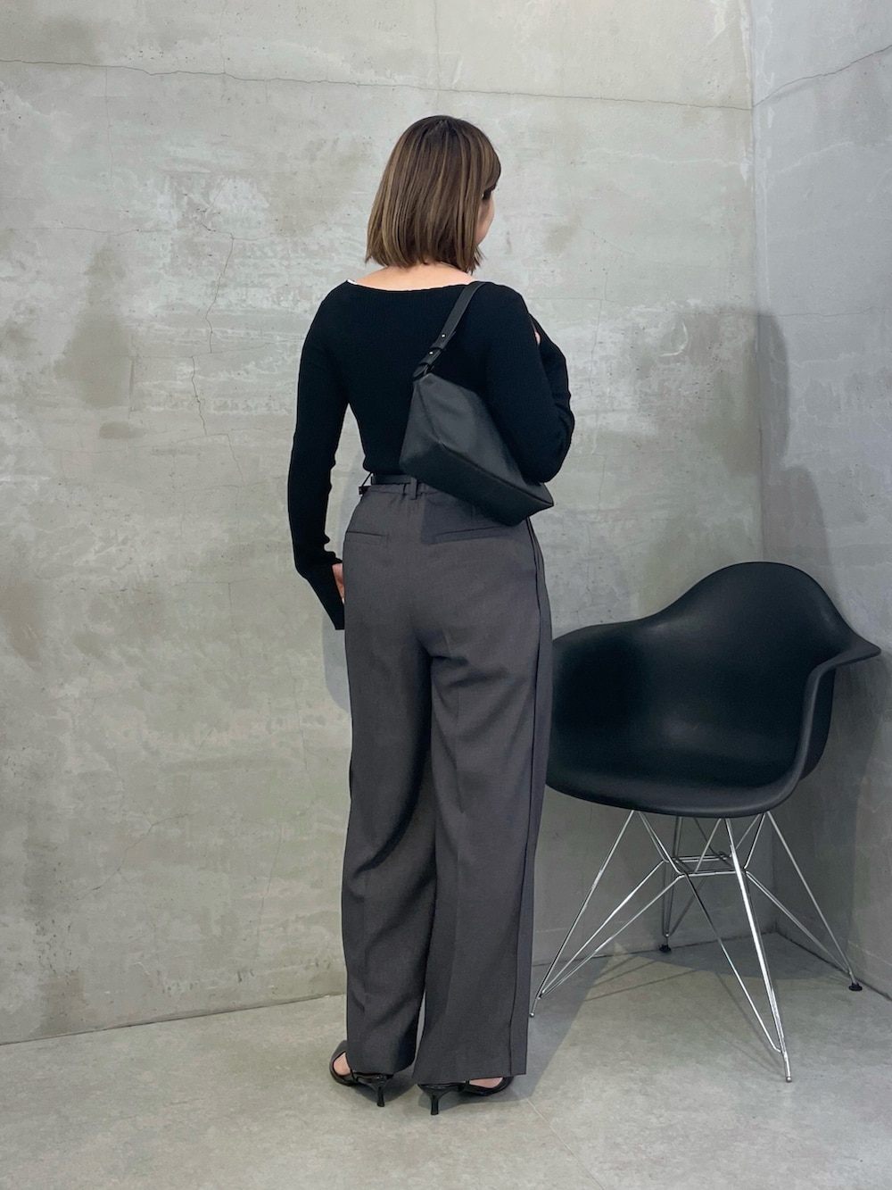 グレー系のスラックス、ブラック系のニット/セーター、シルバー系のネックレスを着用したレディースの秋コーディネートの3枚目の写真