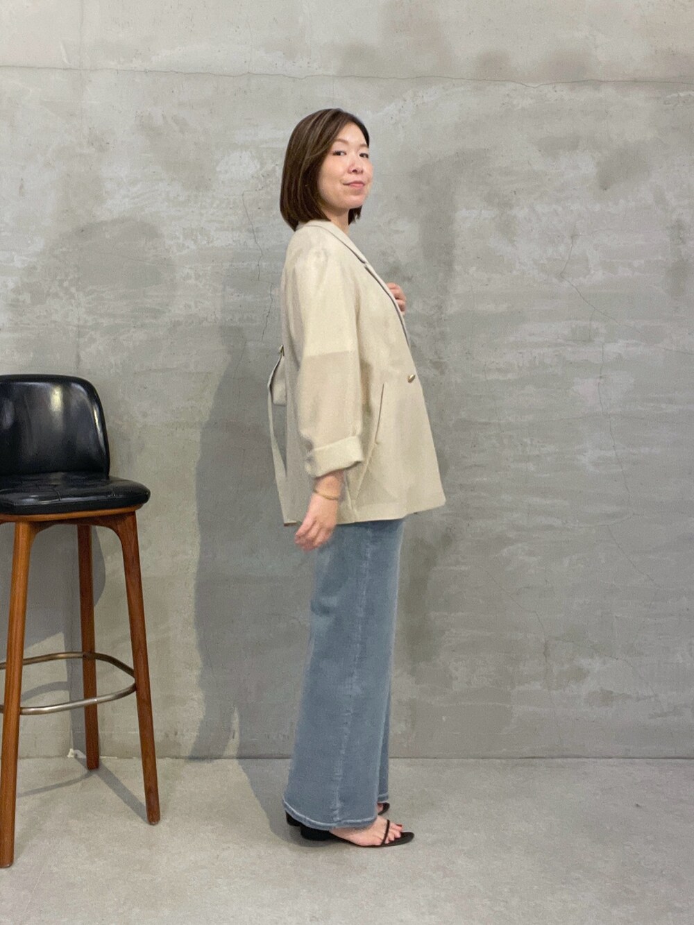 ブルー系のデニムパンツ、ベージュ系のテーラードジャケット、ホワイト系のショルダーバッグを着用したレディースの夏コーディネートの2枚目の写真