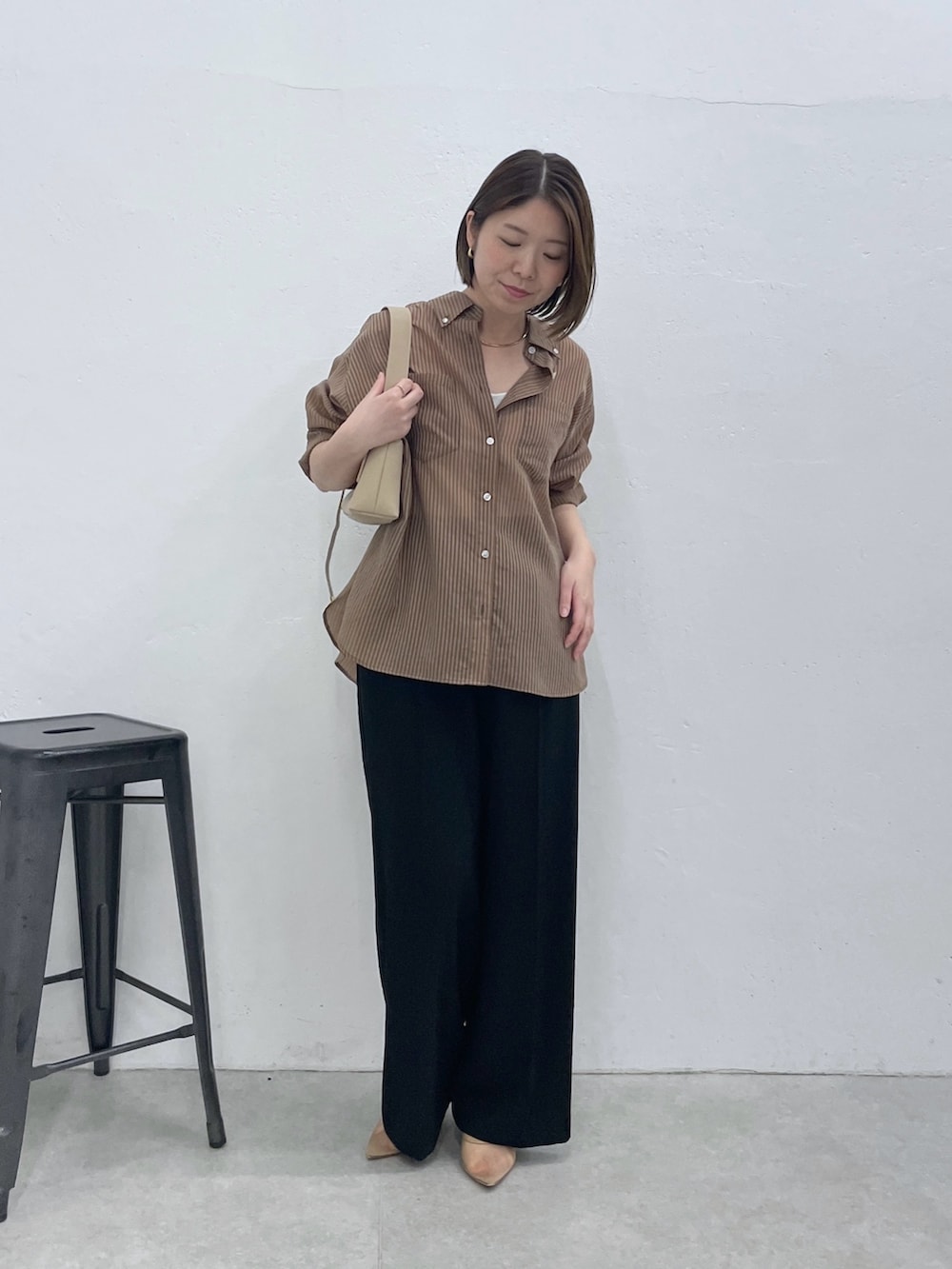 ブラウン系のシャツ/ブラウス、ブラック系のスラックス、ベージュ系のショルダーバッグを着用したレディースの春コーディネートの4枚目の写真
