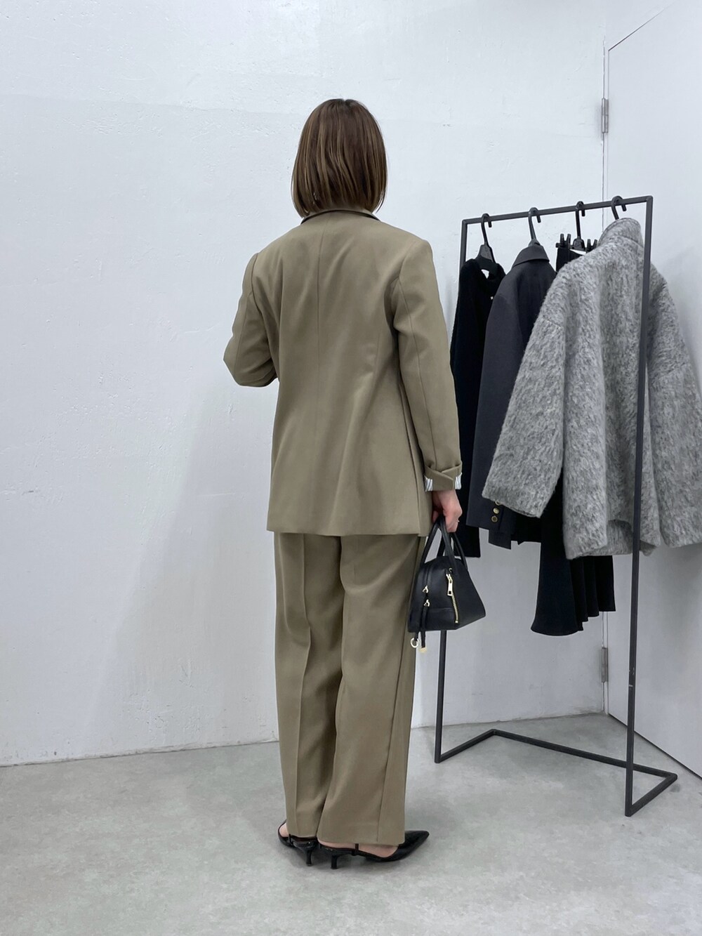 ベージュ系のスラックス、ブラック系のニット/セーター、ベージュ系のテーラードジャケットを着用したレディースの冬コーディネートの3枚目の写真