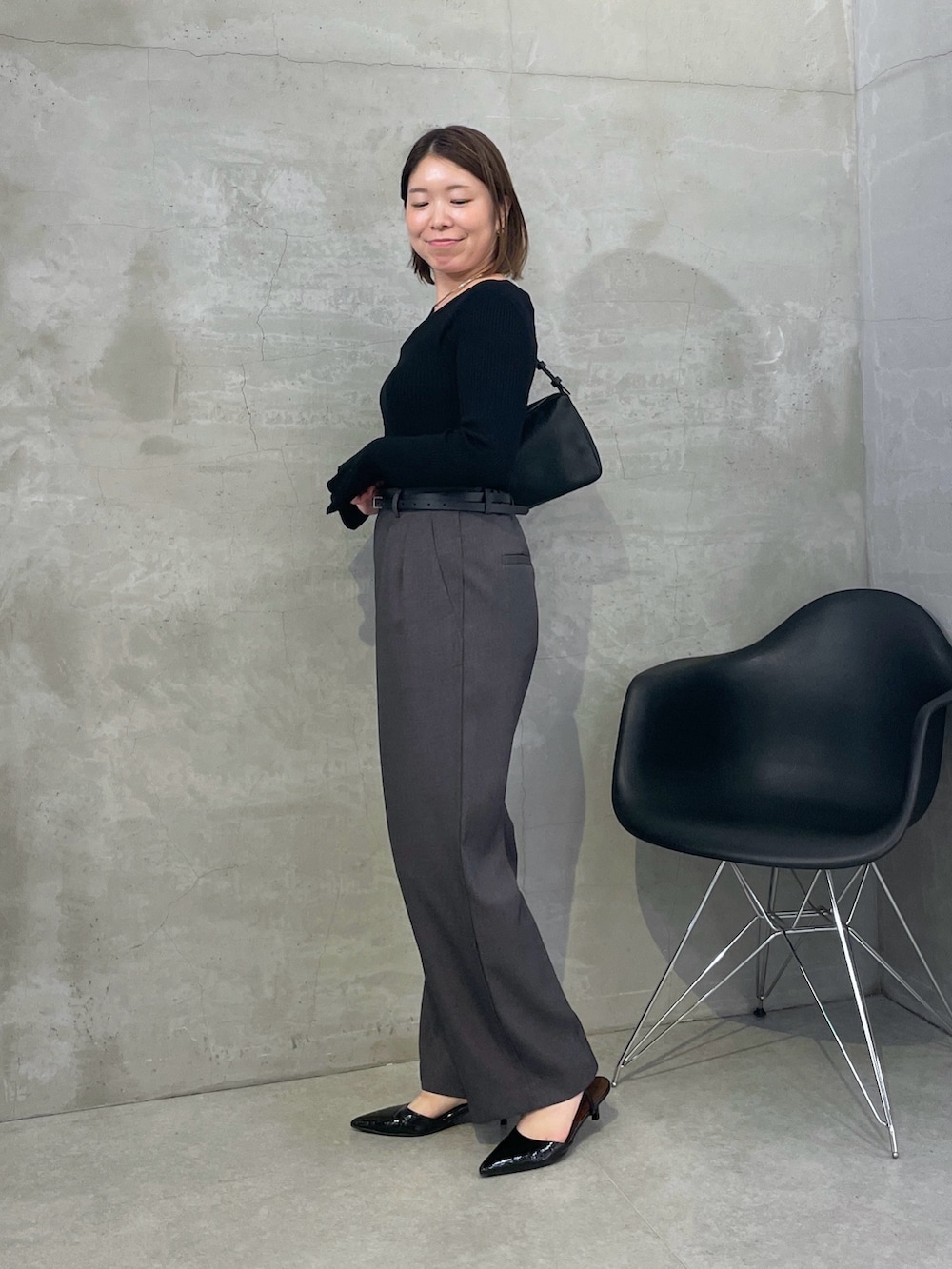 グレー系のスラックス、ブラック系のニット/セーター、シルバー系のネックレスを着用したレディースの秋コーディネートの2枚目の写真