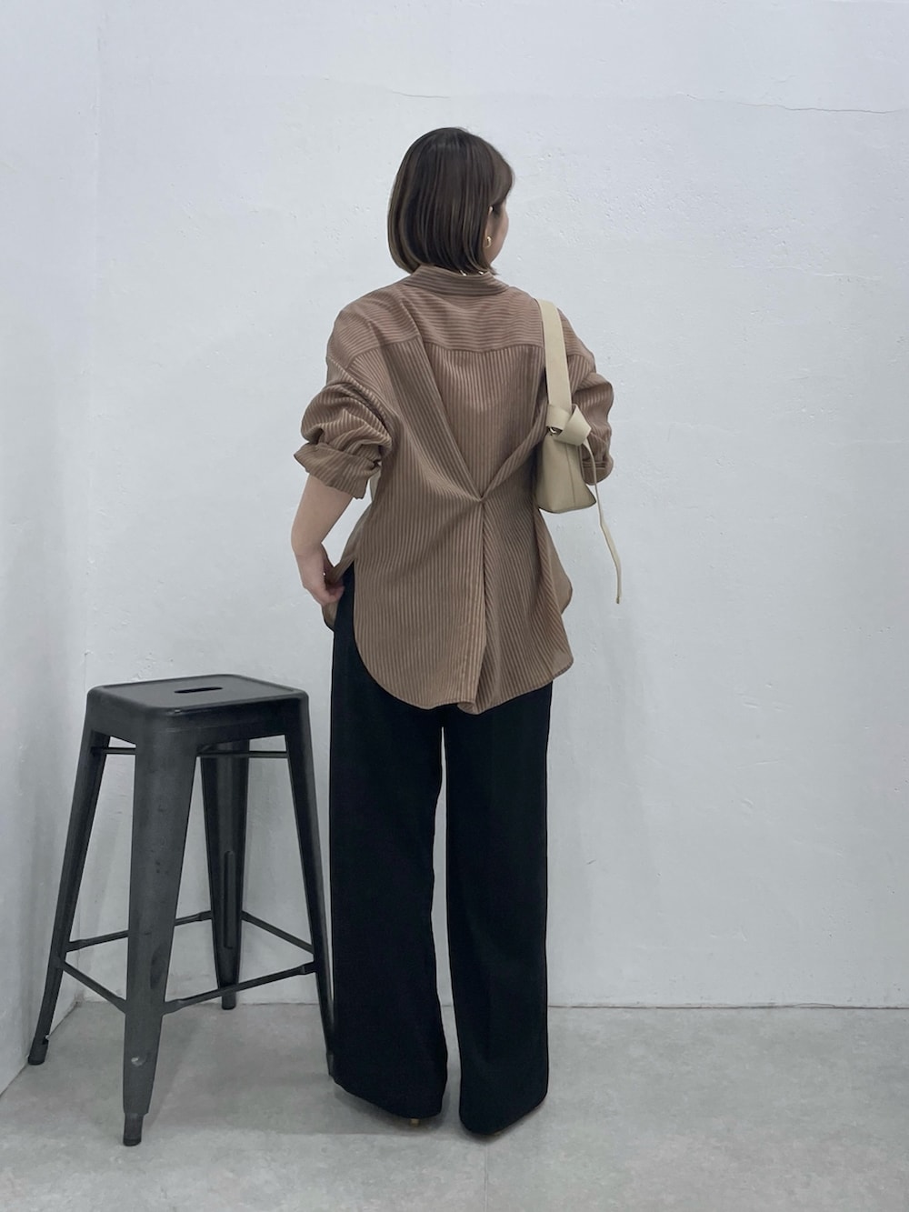 ブラウン系のシャツ/ブラウス、ブラック系のスラックス、ベージュ系のショルダーバッグを着用したレディースの春コーディネートの3枚目の写真