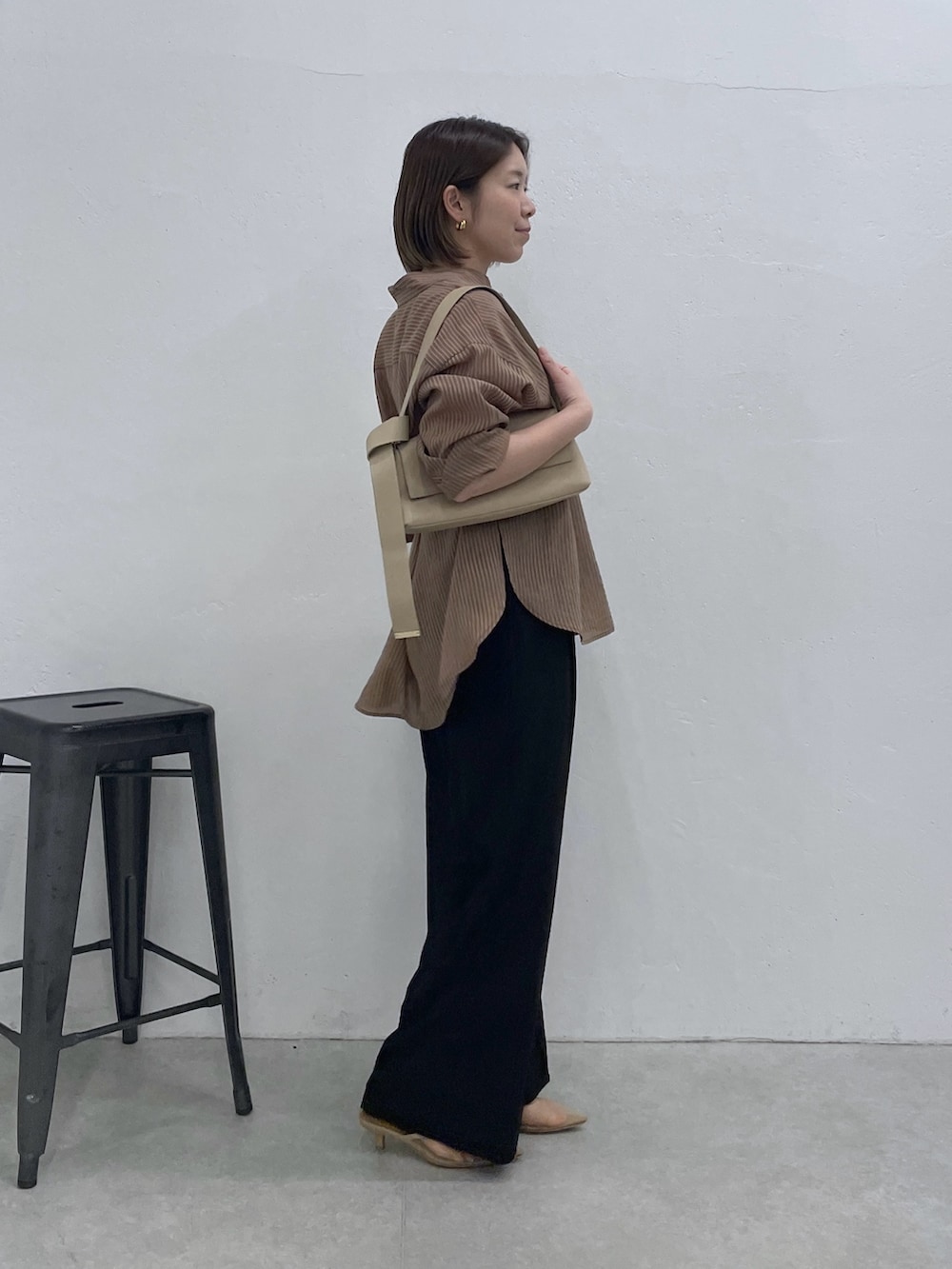 ブラウン系のシャツ/ブラウス、ブラック系のスラックス、ベージュ系のショルダーバッグを着用したレディースの春コーディネートの2枚目の写真