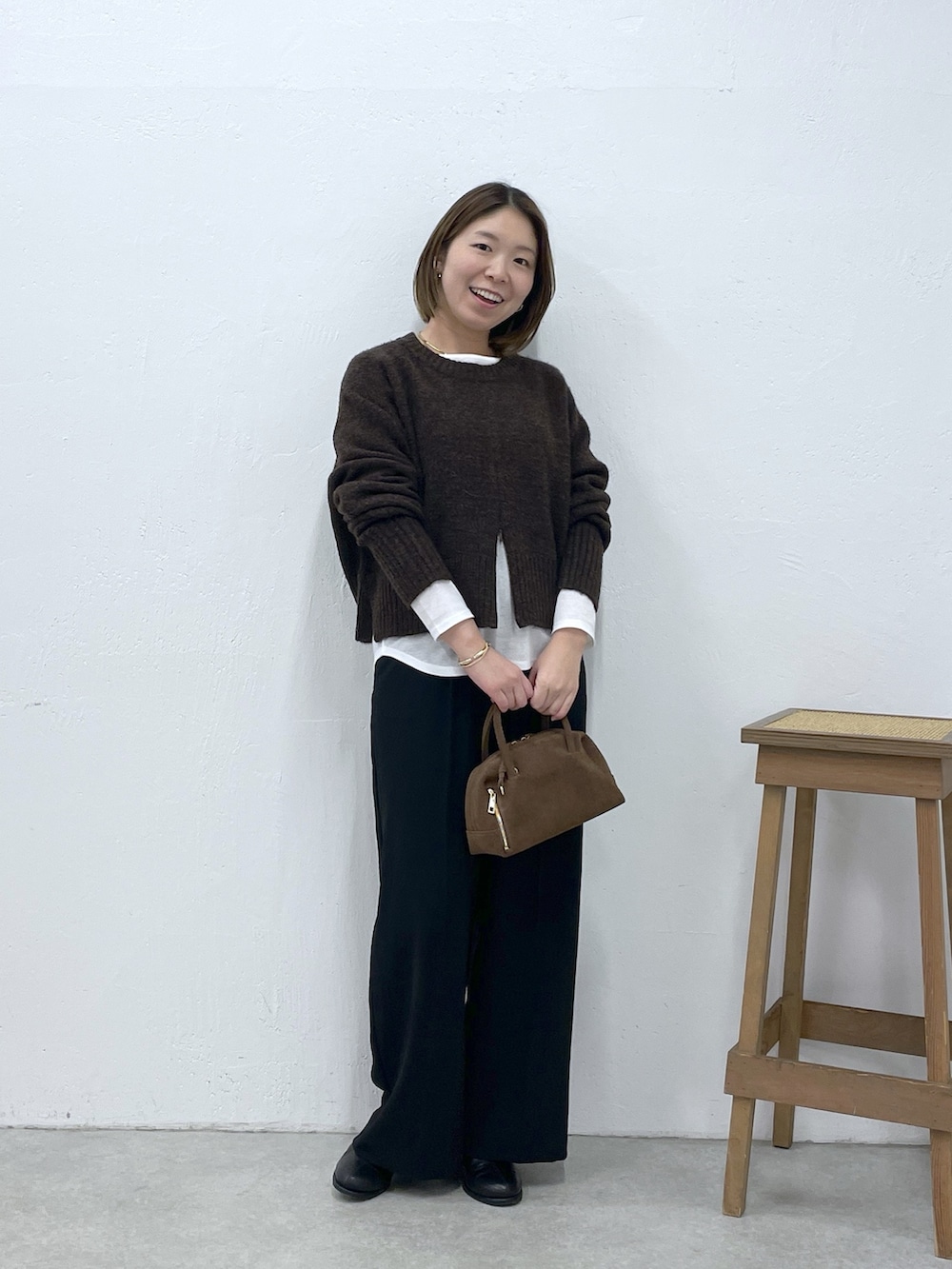 ホワイト系のTシャツ/カットソー、ブラウン系のニット/セーター、ブラック系のスラックスを着用したレディースの冬コーディネートの5枚目の写真