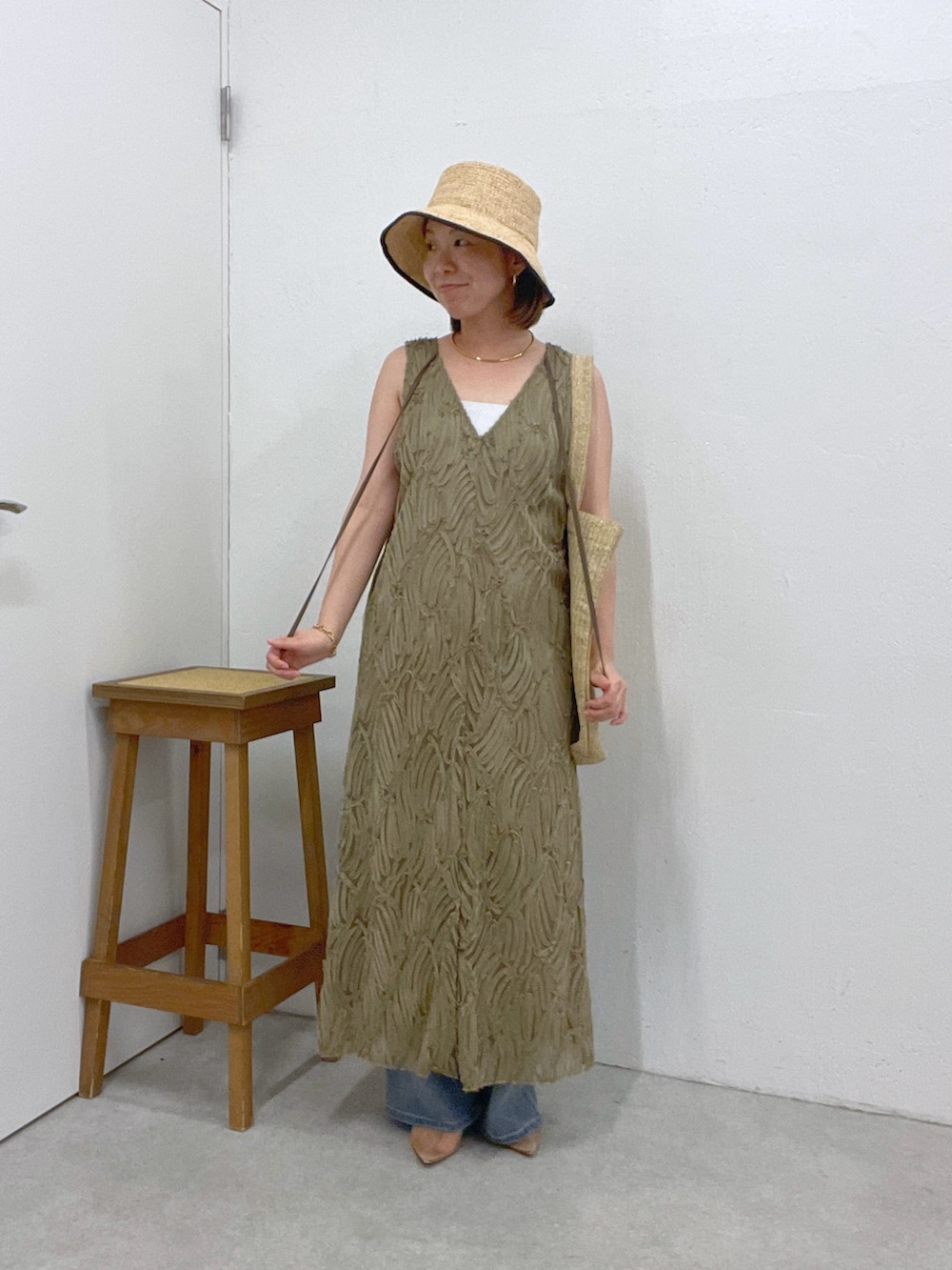 ブルー系のデニムパンツ、グリーン系のワンピース、ベージュ系のトートバッグを着用したレディースの夏コーディネートの4枚目の写真