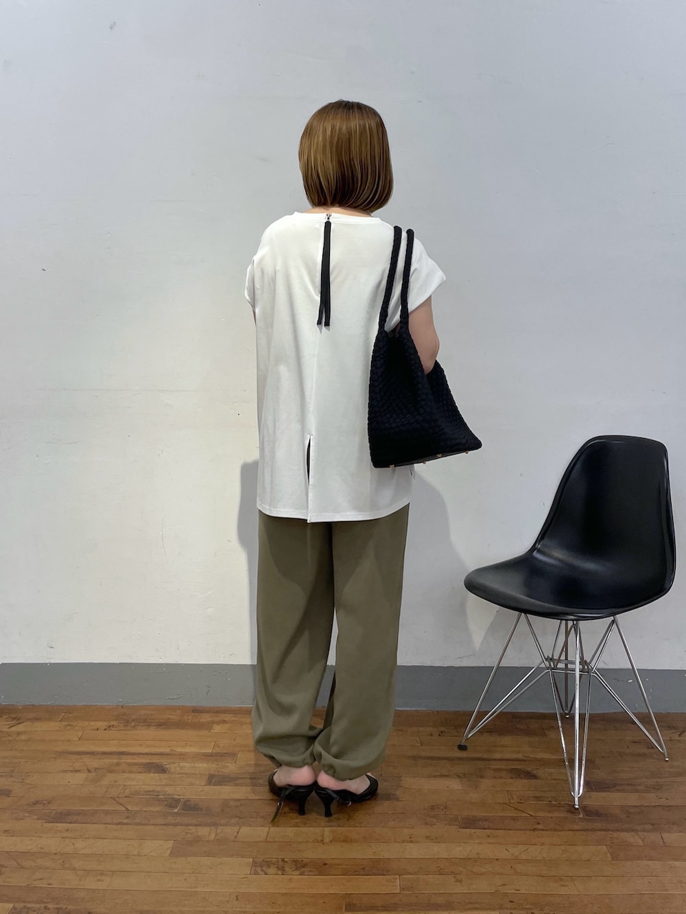 ブラック系のトートバッグ、ホワイト系のTシャツ/カットソー、グリーン系のスラックスを着用したレディースの夏コーディネートの3枚目の写真
