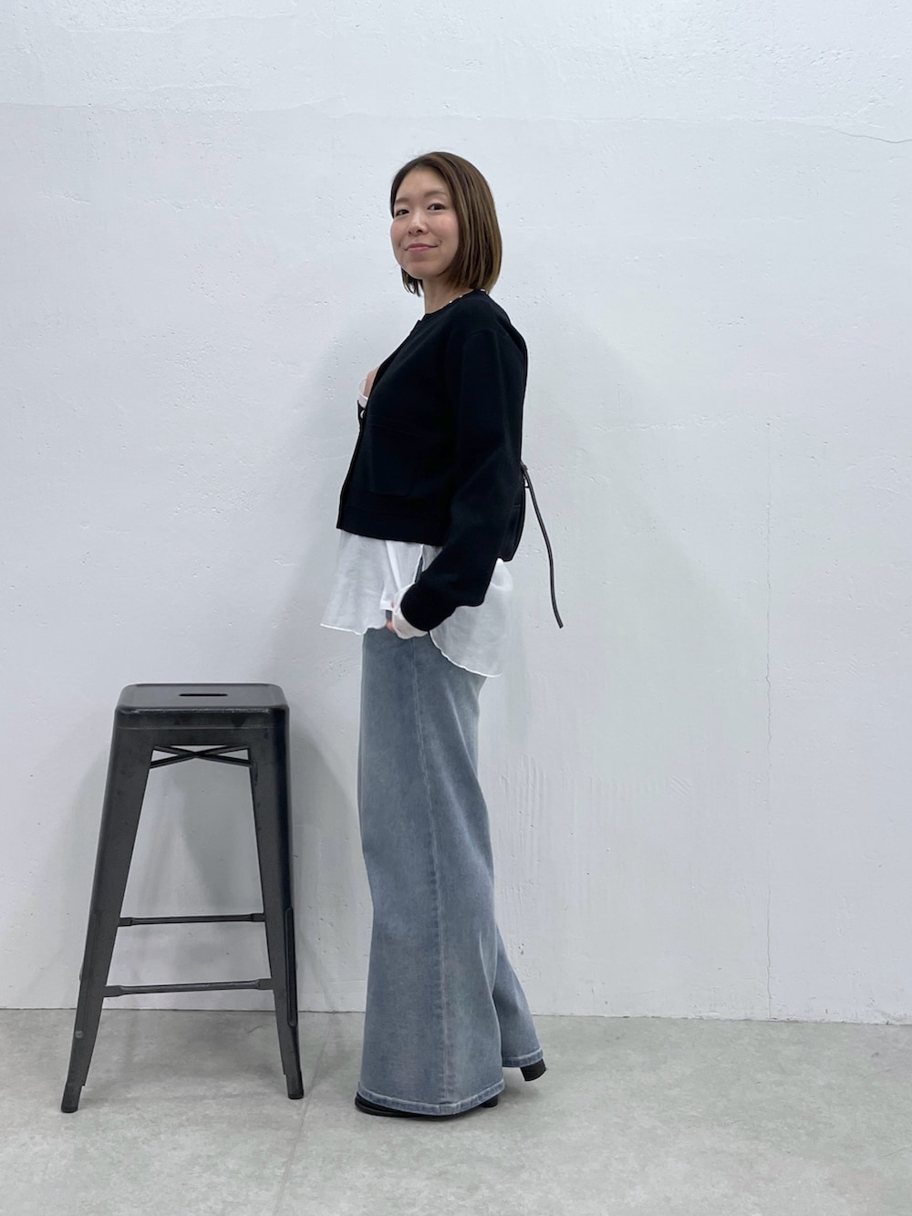 ブラック系のカーディガン/ボレロ、ホワイト系のTシャツ/カットソー、ブルー系のデニムパンツを着用したレディースの冬コーディネートの2枚目の写真