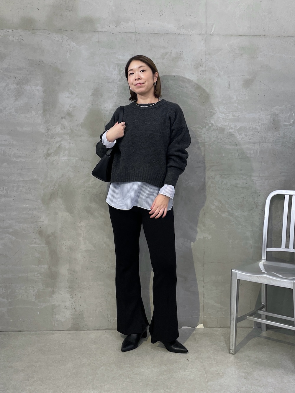 グレー系のニット/セーター、ホワイト系のTシャツ/カットソー、ブラック系のスラックスを着用したレディースの秋コーディネートの5枚目の写真