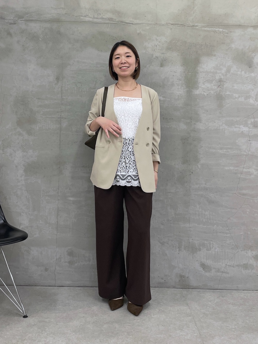 ベージュ系のノーカラージャケット、ホワイト系のキャミソール、ブラウン系のスラックスを着用したレディースの冬コーディネートの5枚目の写真