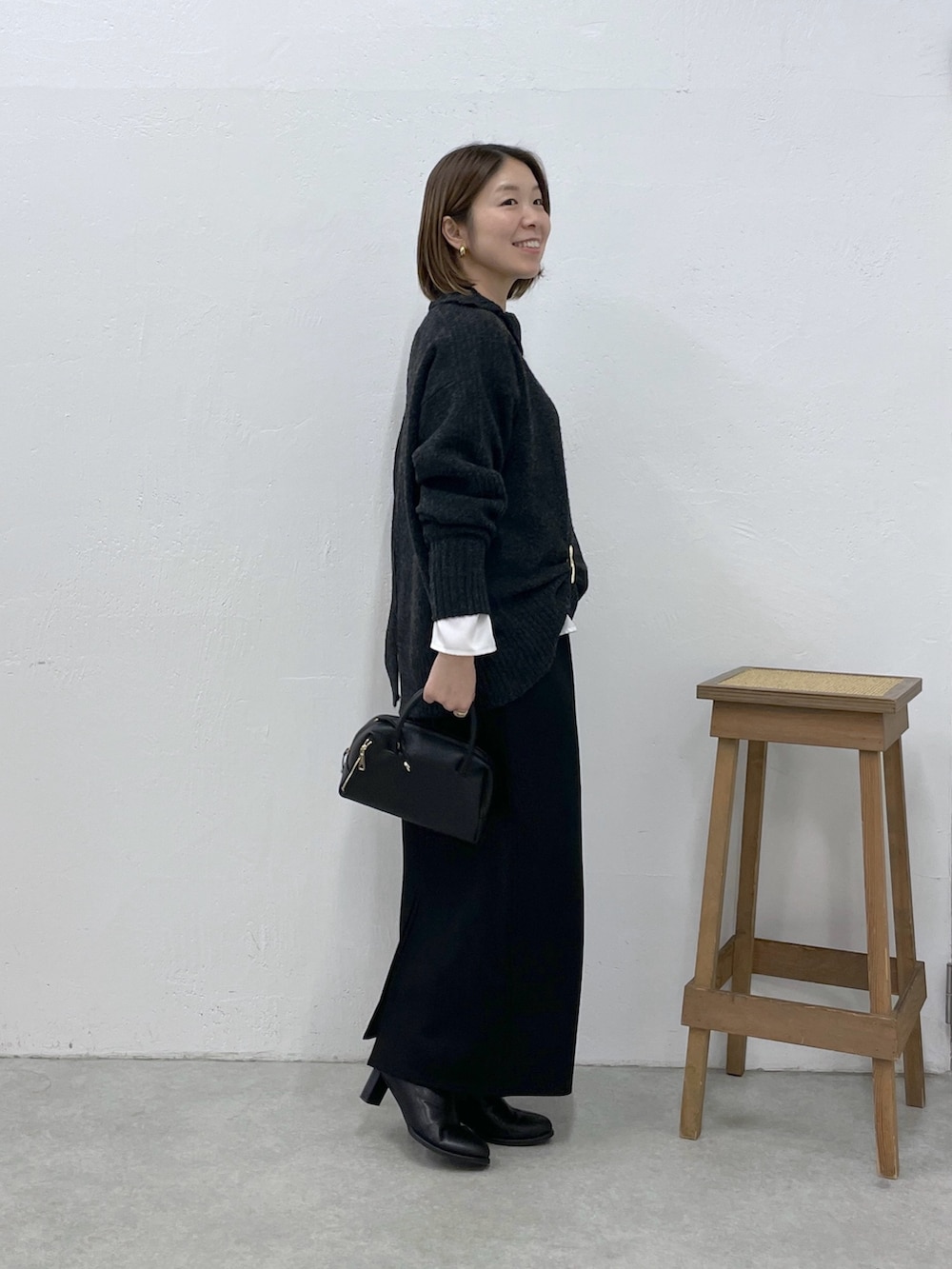グレー系のニット/セーター、ホワイト系のシャツ/ブラウス、ブラック系のスカートを着用したレディースの冬コーディネートの2枚目の写真