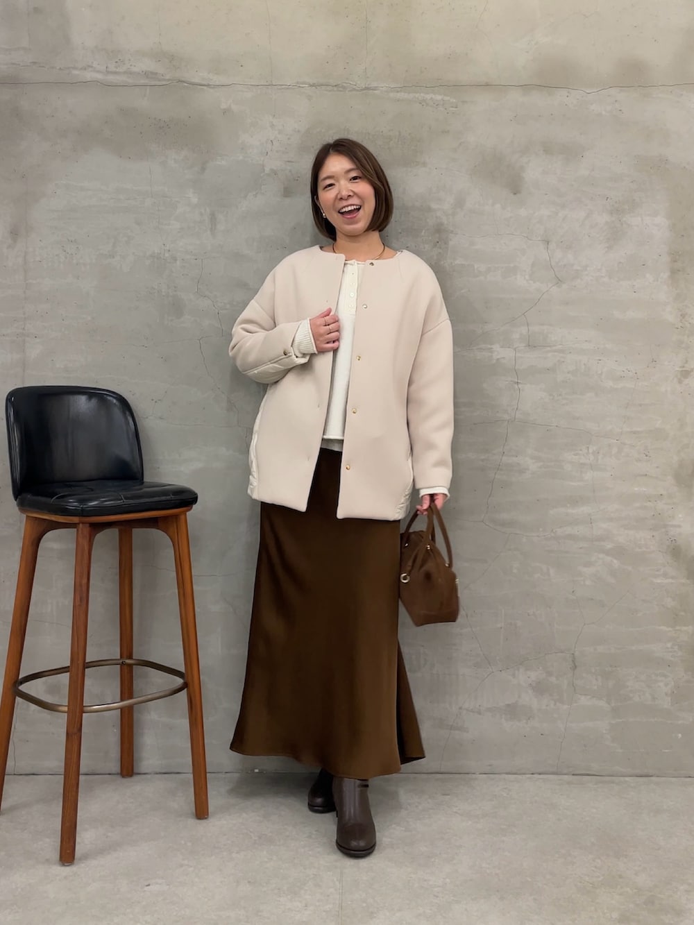 ブラウン系のスカート、ホワイト系のTシャツ/カットソー、ホワイト系のニット/セーターを着用したレディースの秋コーディネートの4枚目の写真