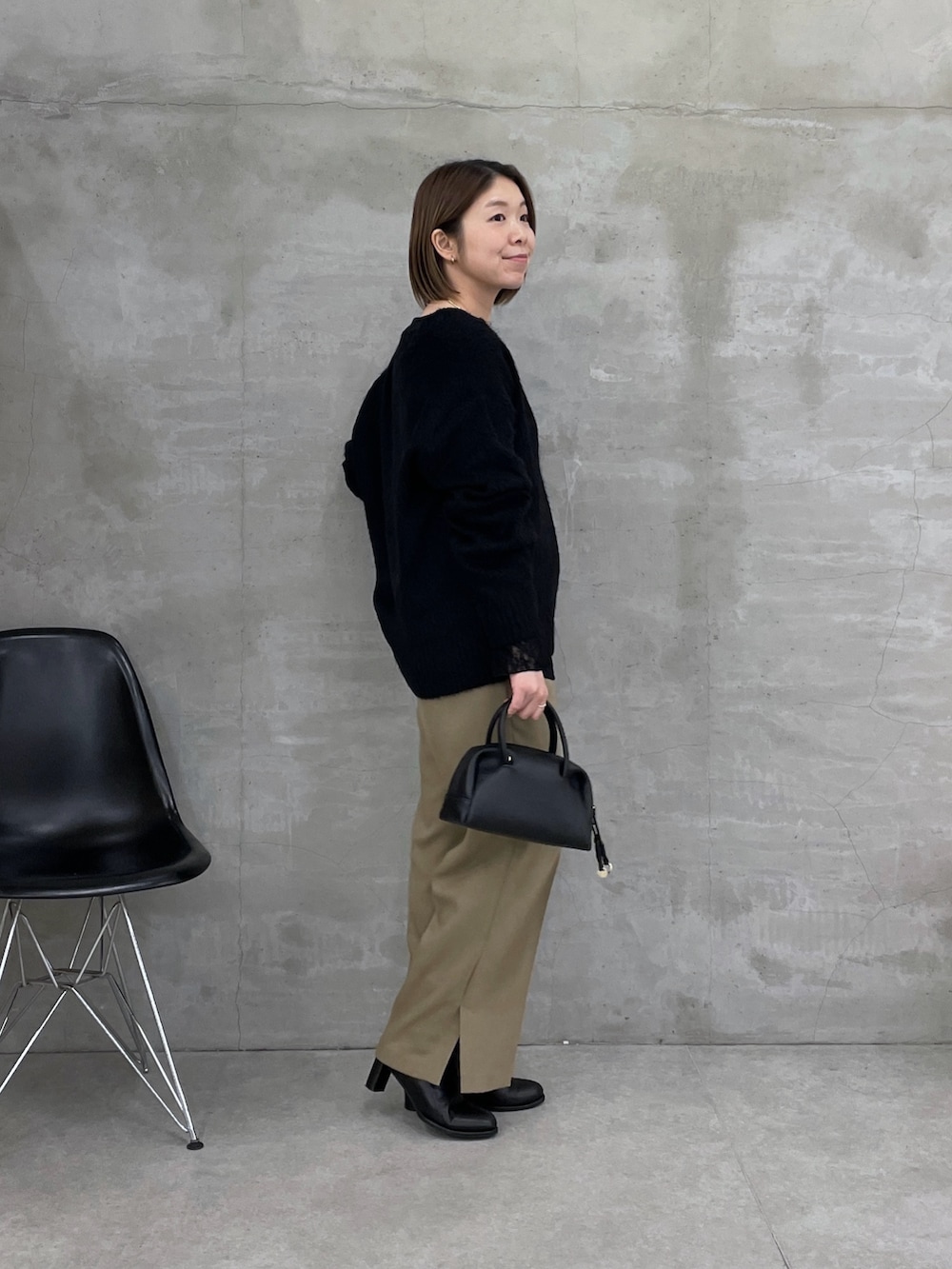 ブラック系のニット/セーター、ブラック系のTシャツ/カットソー、ベージュ系のスラックスを着用したレディースの冬コーディネートの4枚目の写真