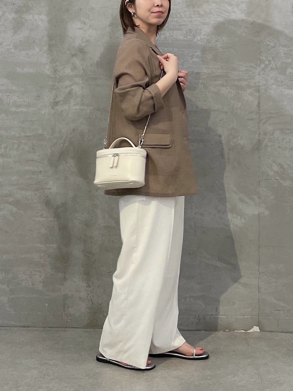 ベージュ系のテーラードジャケット、ホワイト系のキャミソール、ホワイト系のスラックスを着用したレディースの春コーディネートの3枚目の写真