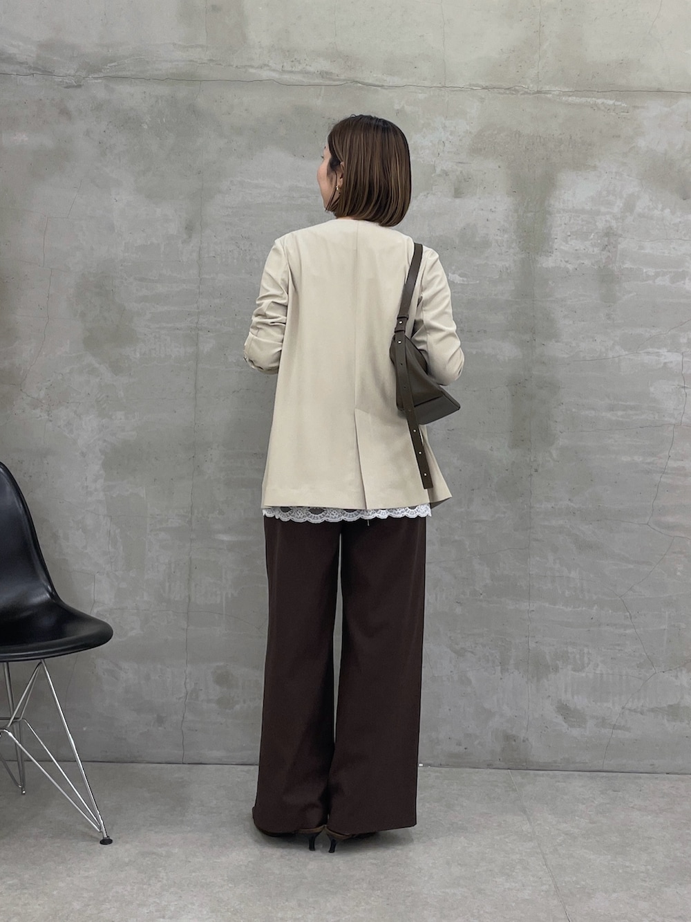ベージュ系のノーカラージャケット、ホワイト系のキャミソール、ブラウン系のスラックスを着用したレディースの冬コーディネートの3枚目の写真